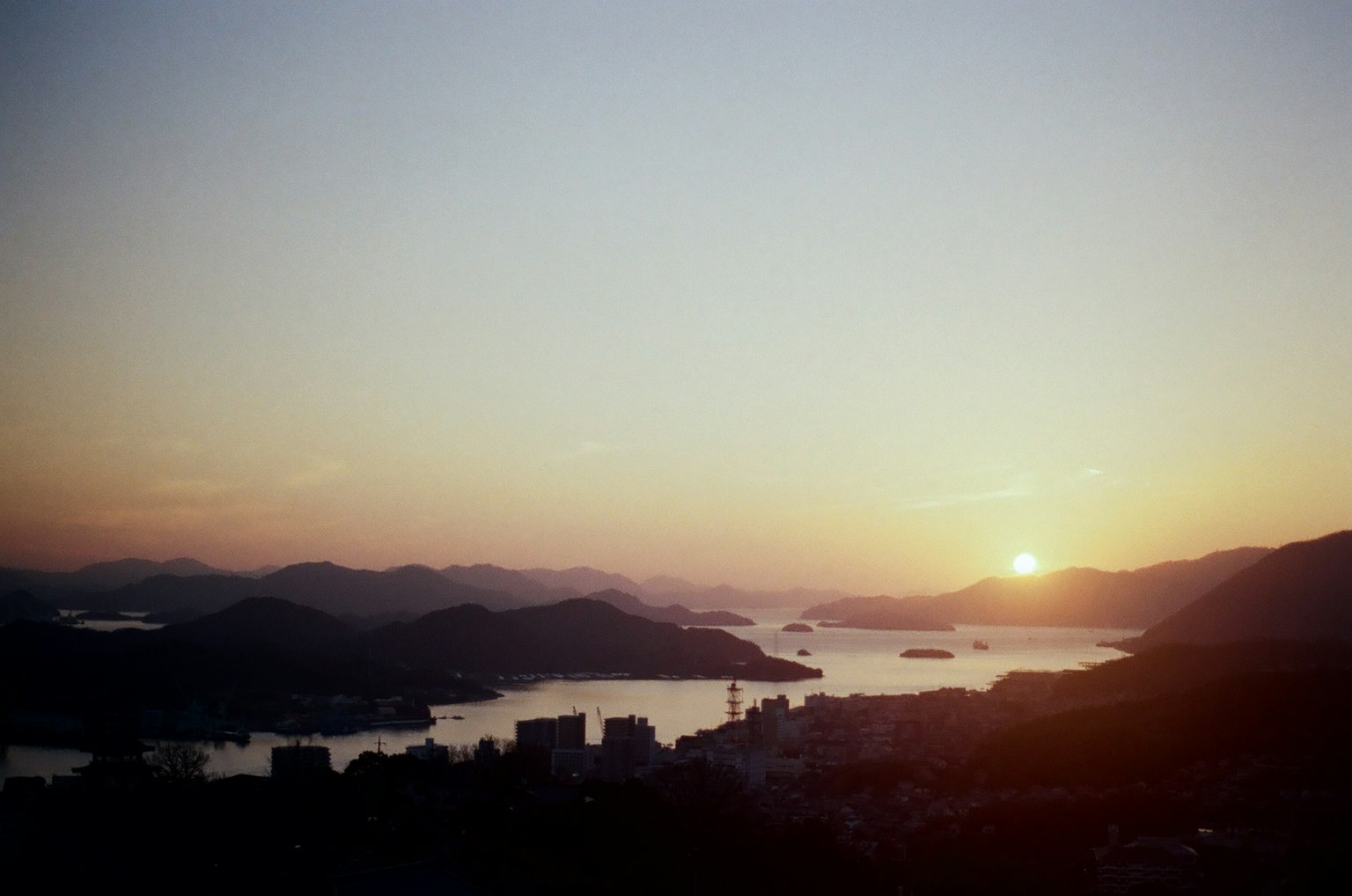 美麗的日落在山和海城市天際線的輪廓上