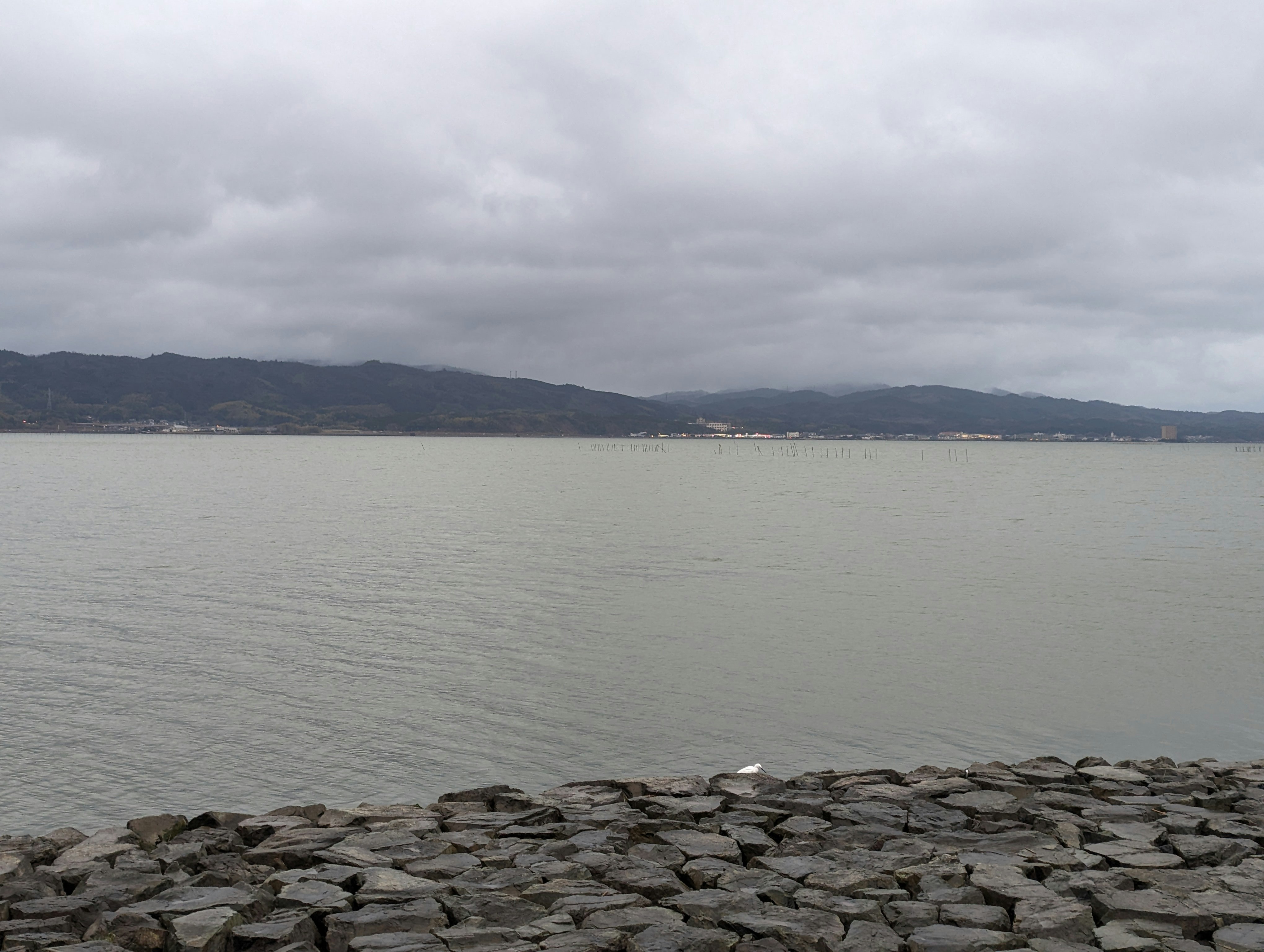 防波堤の石積みと湖面、曇り空の景色