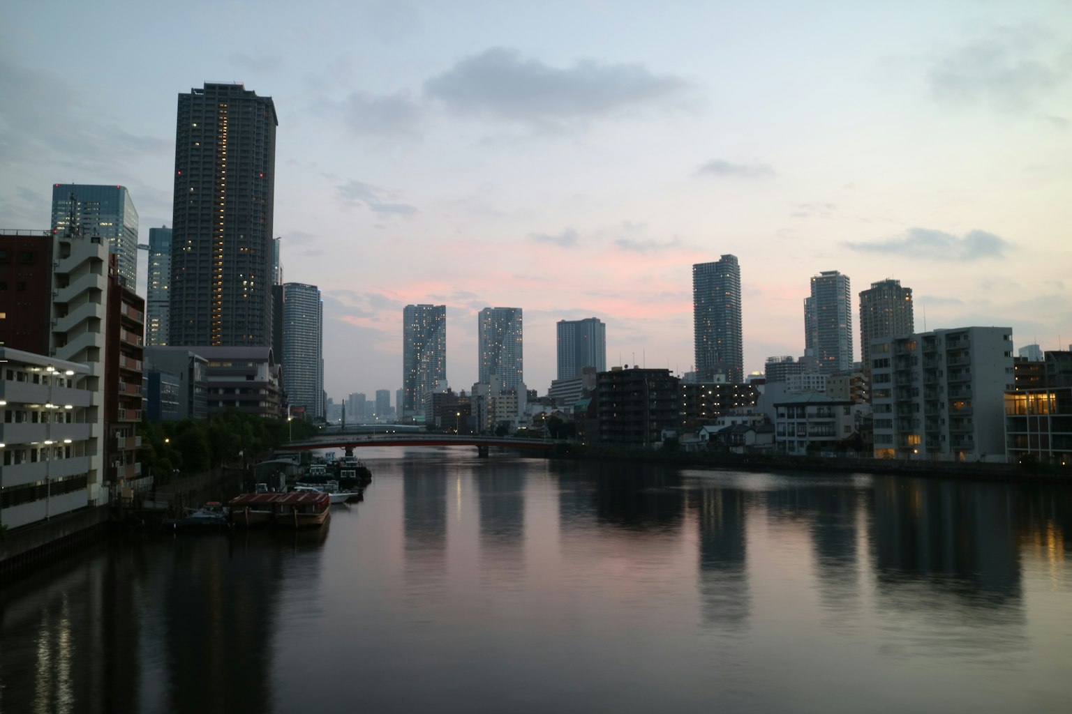 ภาพทิวทัศน์เมืองยามพระอาทิตย์ตกตึกสูงและการสะท้อนในน้ำสงบ