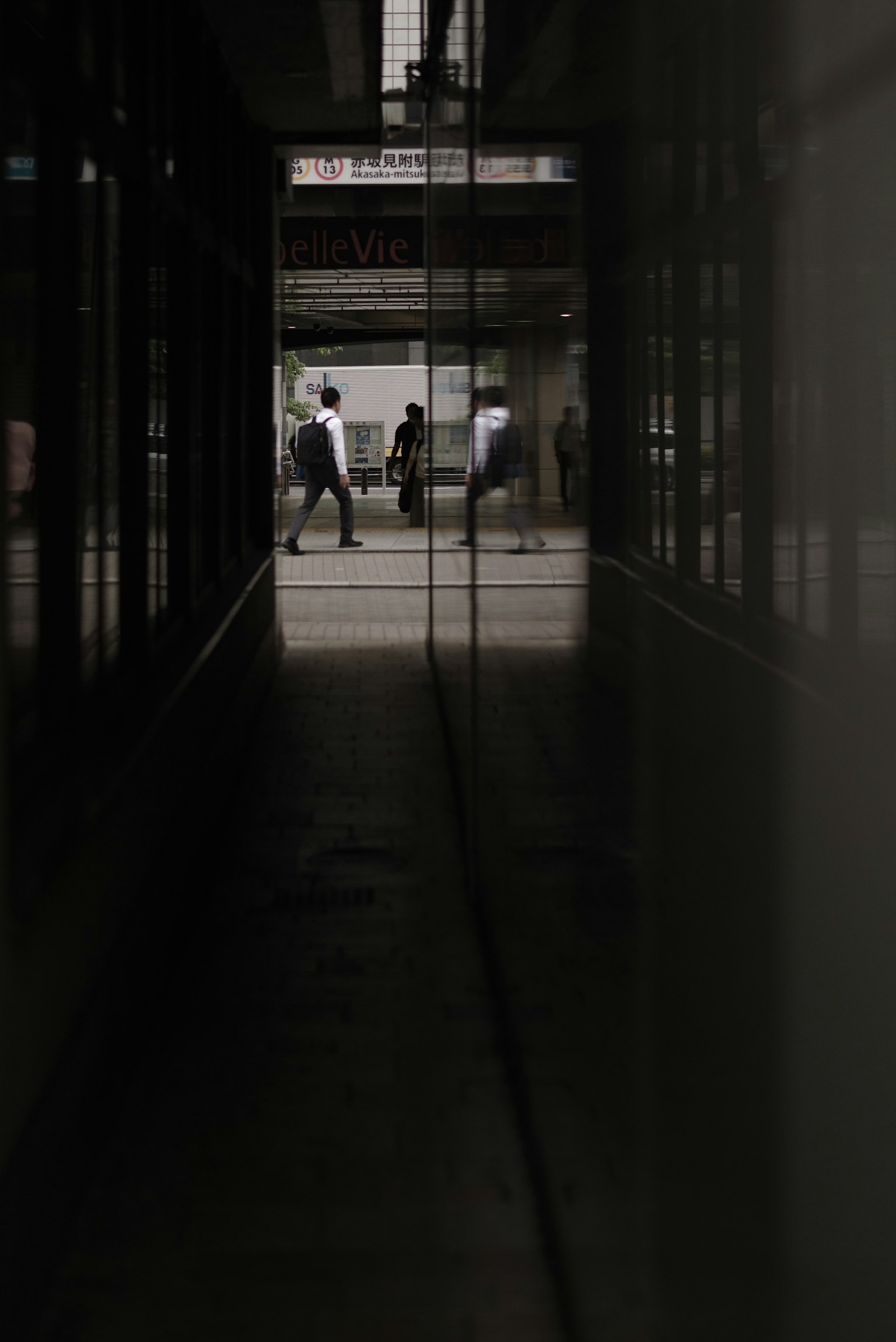 People walking in a dimly lit corridor with reflective surfaces