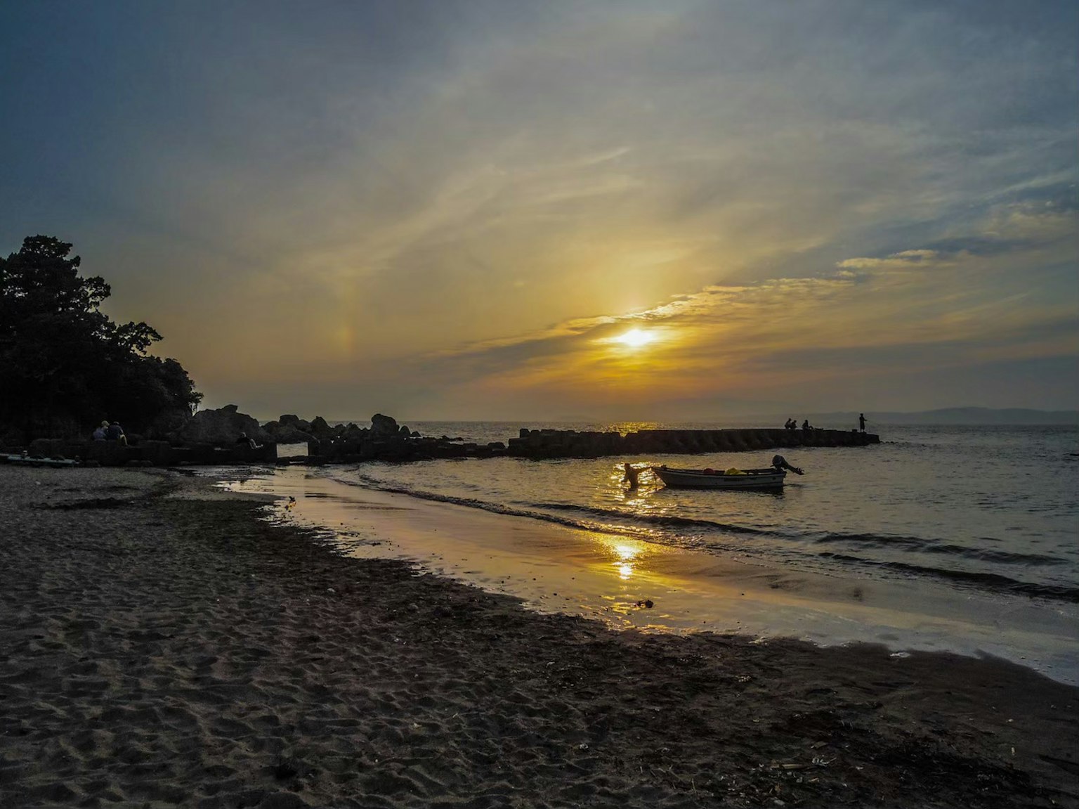 海滩风景，夕阳在水面反射，小船漂浮