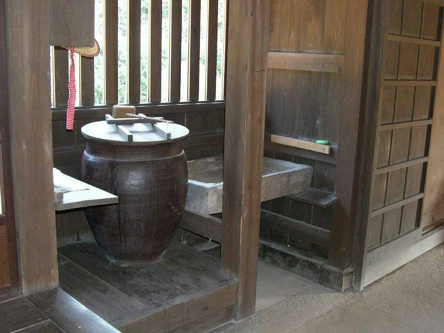 Interno di un bagno giapponese tradizionale circondato da pareti in legno con un bagno in ceramica e un lavandino