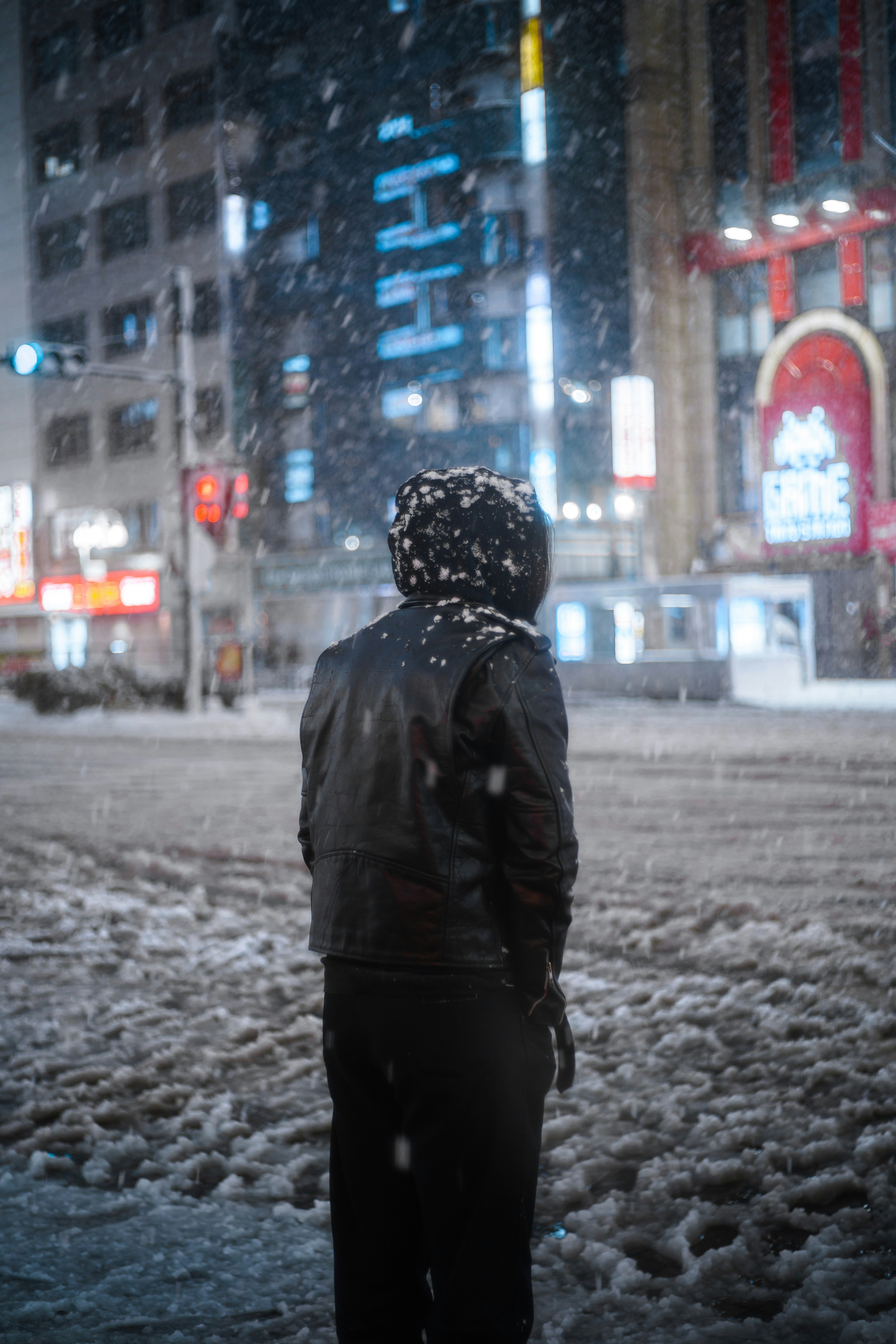 夜晚下雪的城市里，背影撑伞的人