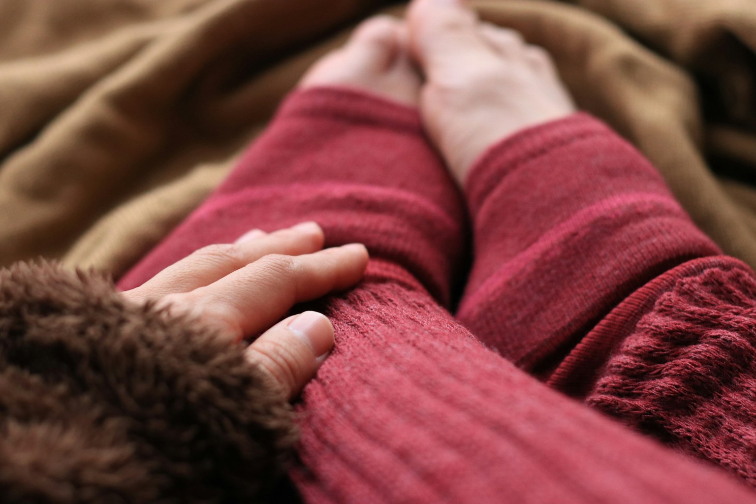 Bàn tay resting trên ống tay đan màu đỏ ấm