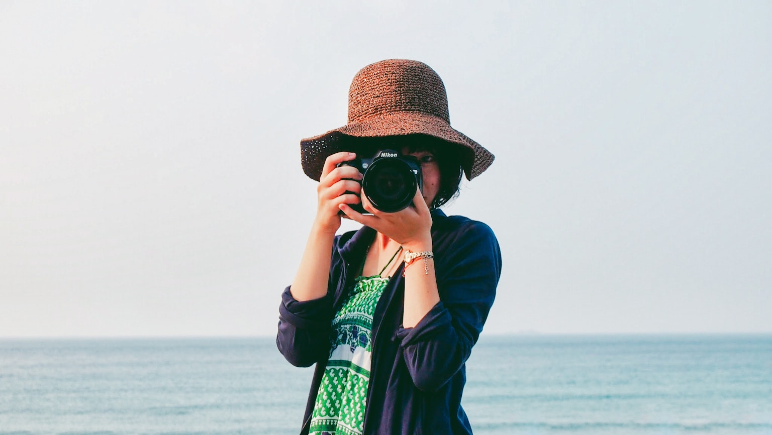 A woman holding a camera at the beach