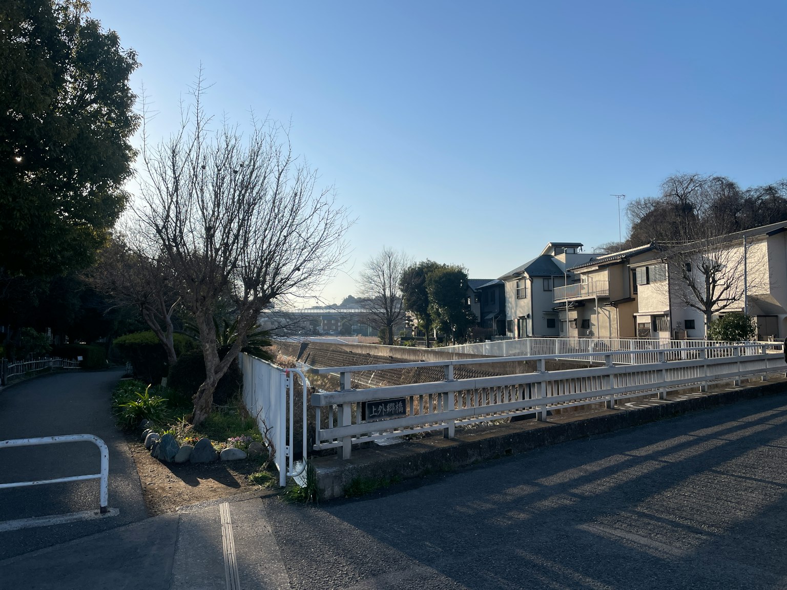 Un paysage avec un quartier résidentiel et un terrain vacant sous un ciel bleu clair