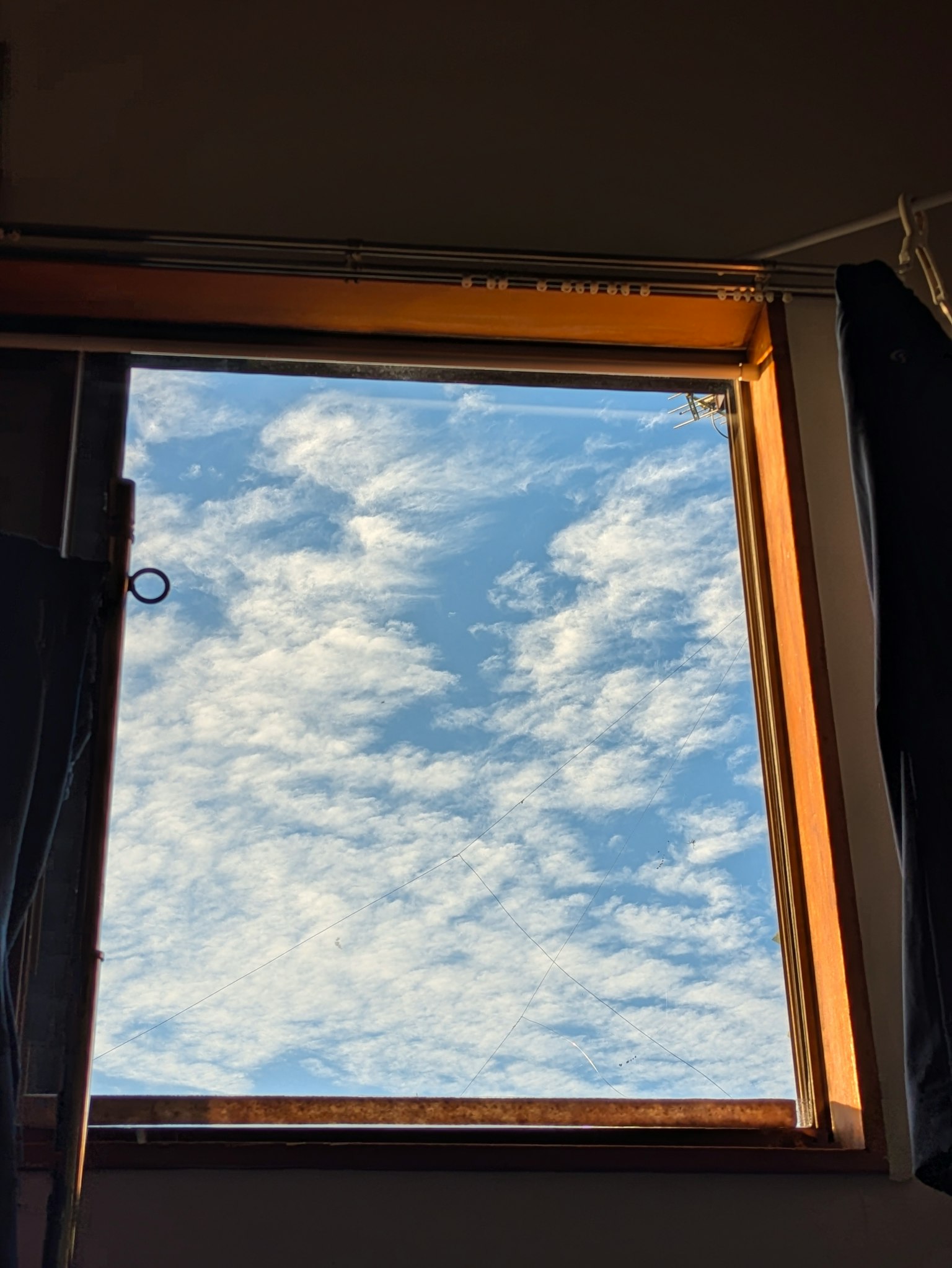 Cảnh nhìn ra bầu trời xanh và mây trắng qua cửa sổ mở