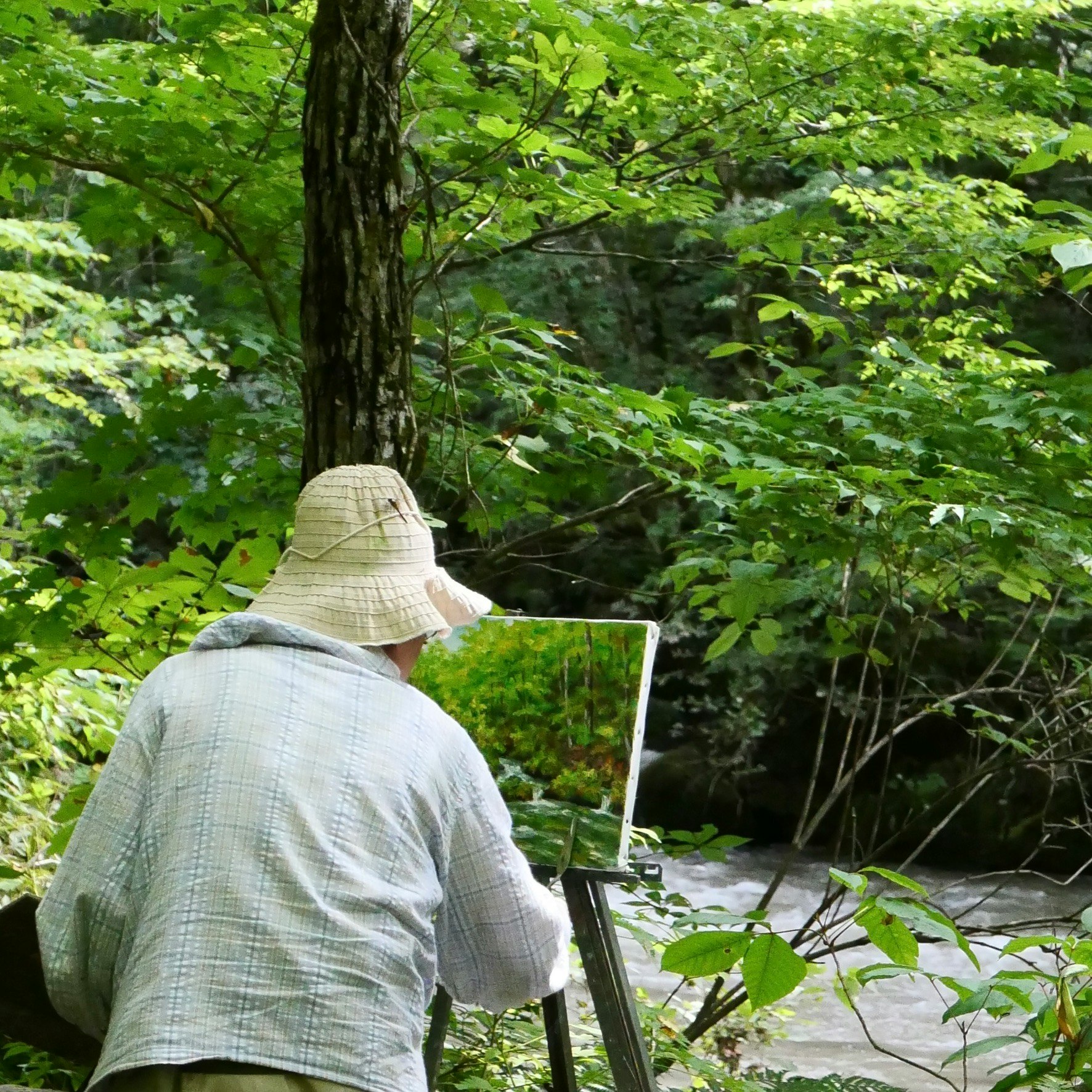 森の緑の中でキャンバスに向かう筆先のある制作風景