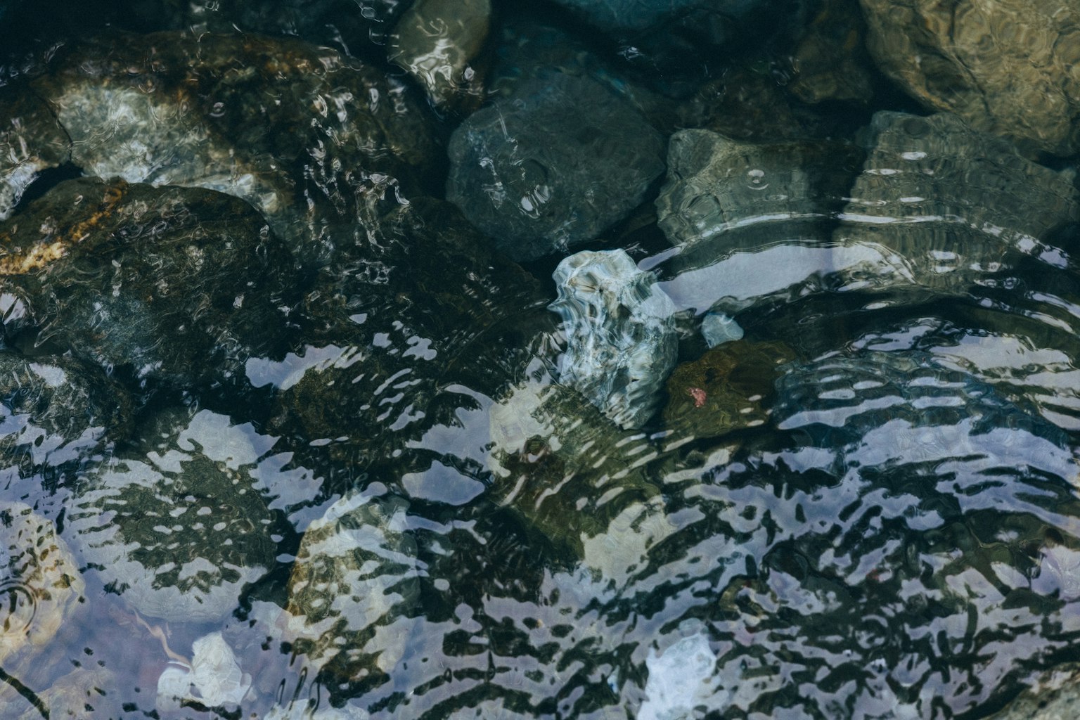 Klare Wasseroberfläche, die Steine und Wellen reflektiert