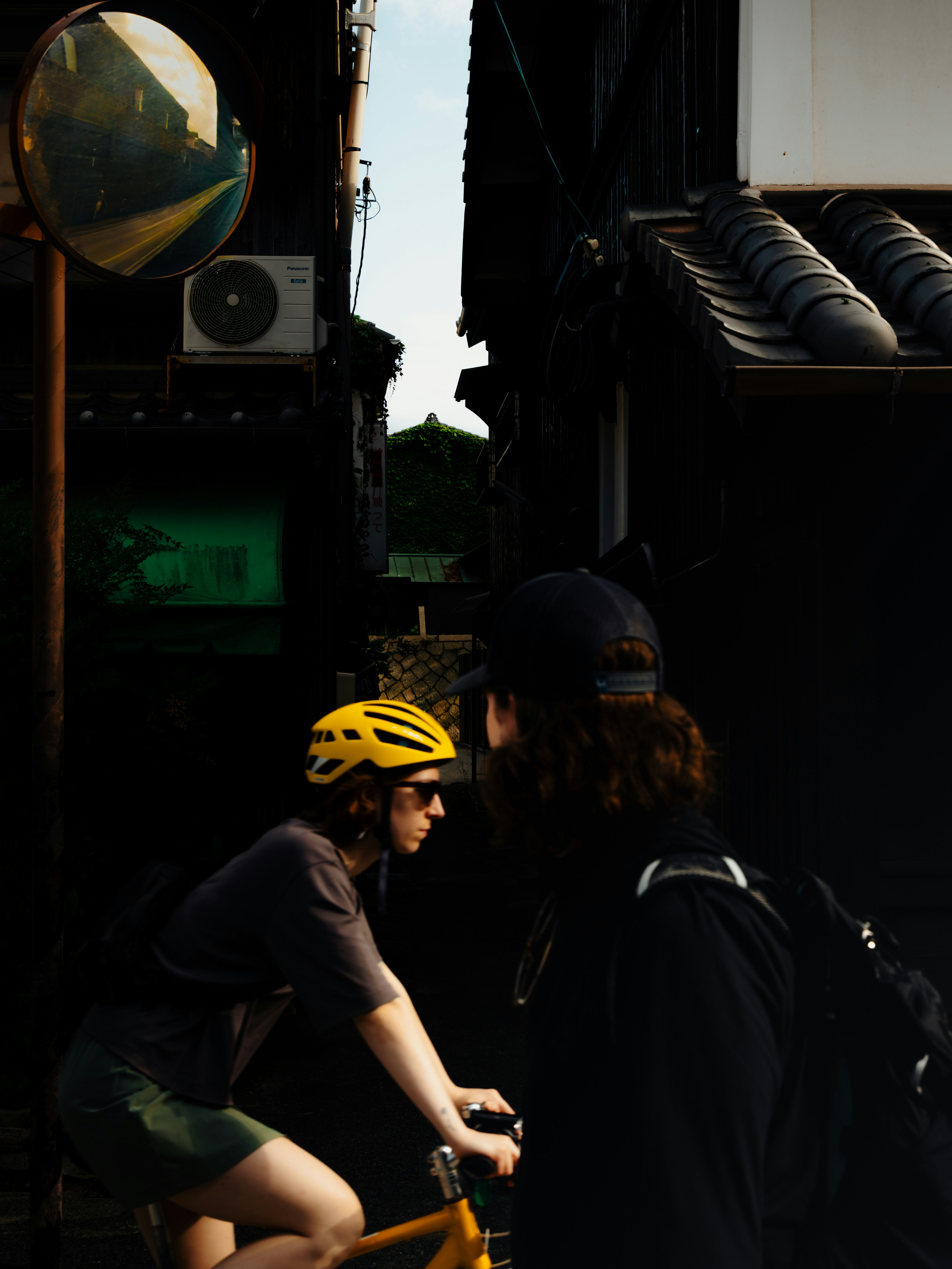 路地の薄暗い街並みで歩く人々と自転車