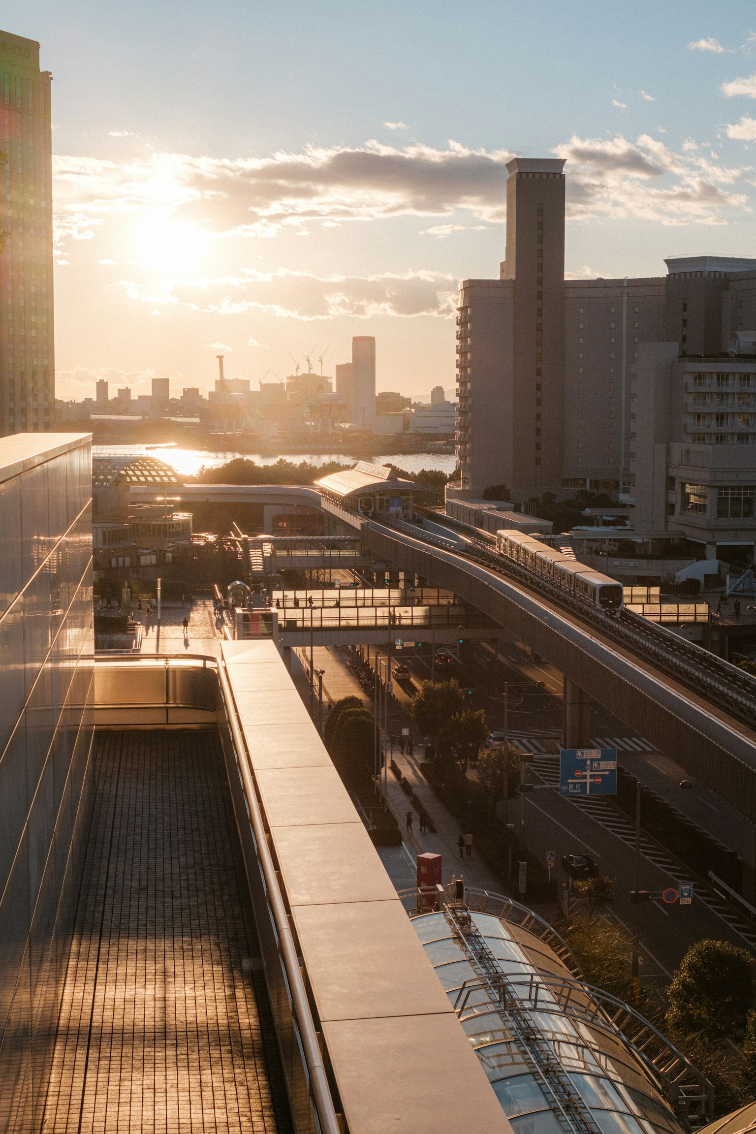 Cityscape at sunset featuring high-rise buildings and monorail