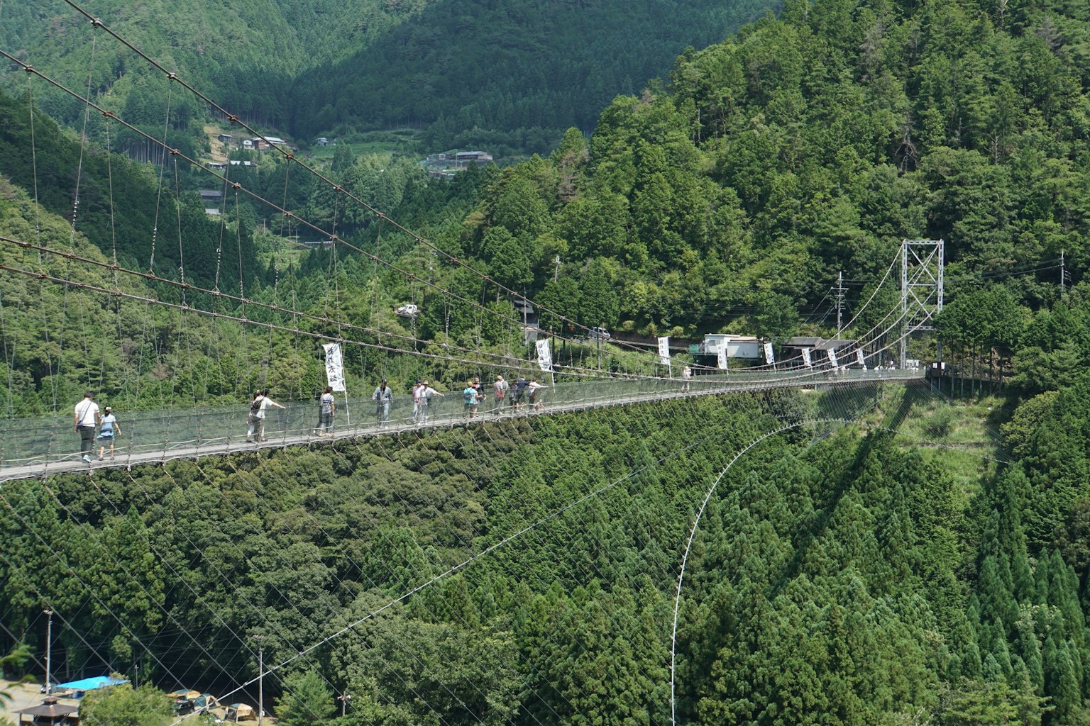 Persone che attraversano un ponte sospeso circondato da montagne verdi