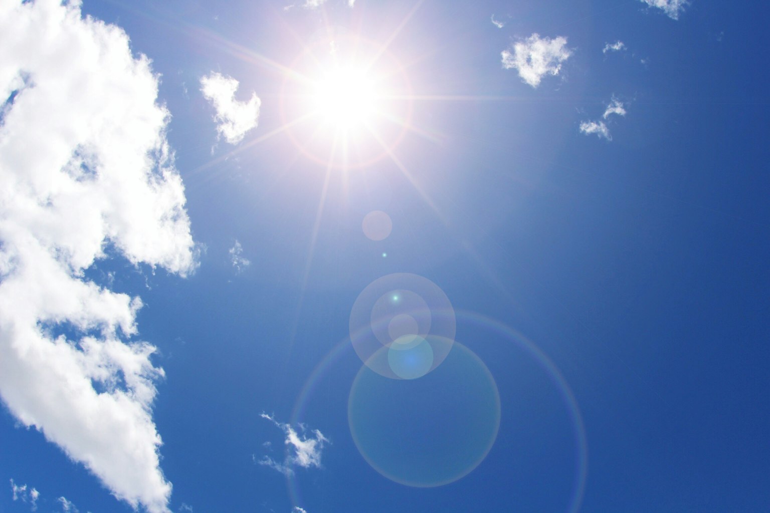 Helle Sonne strahlt in einem klaren blauen Himmel mit flauschigen weißen Wolken