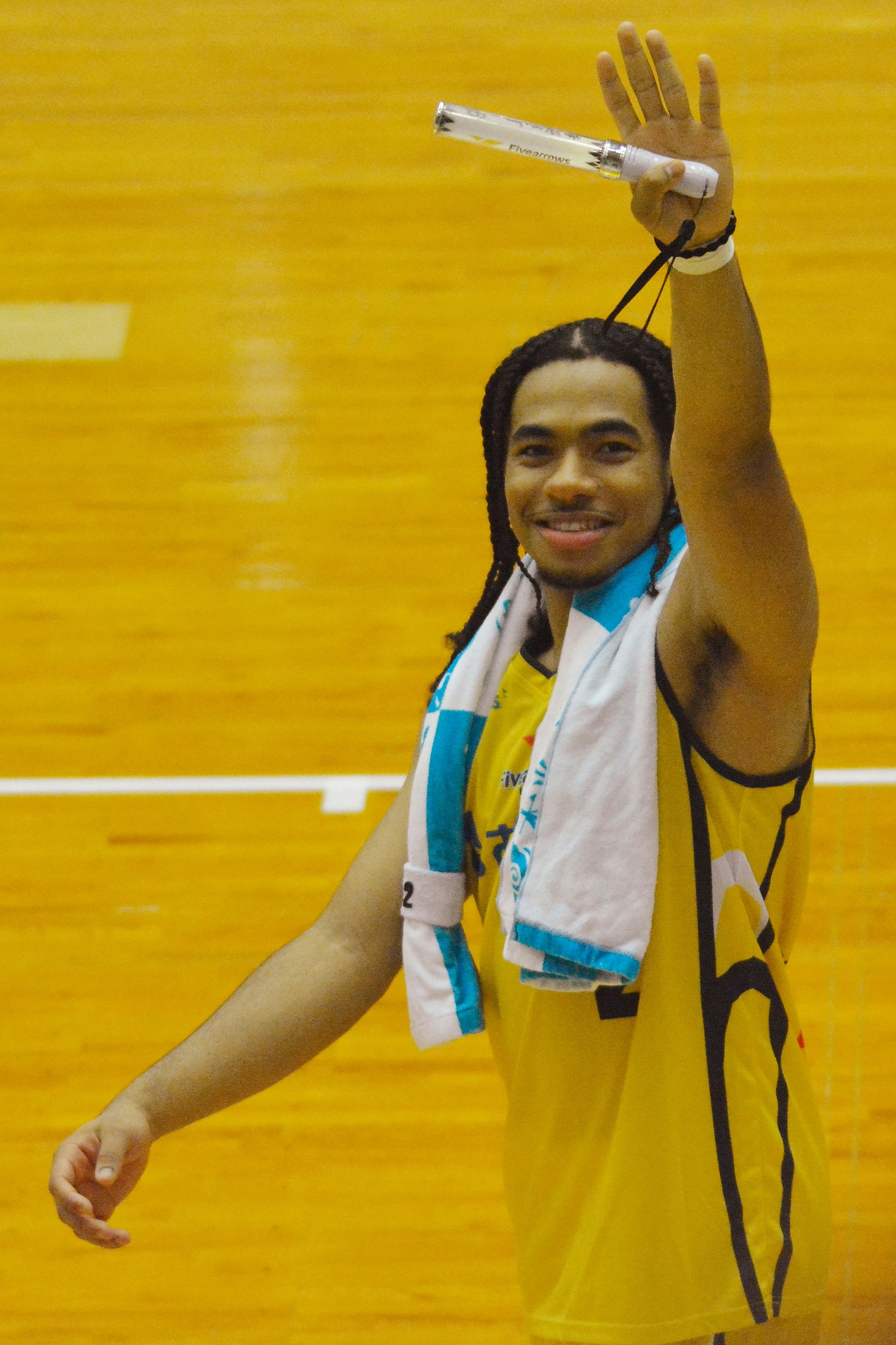 Sourire d’un joueur de basket tenant une serviette de supporters