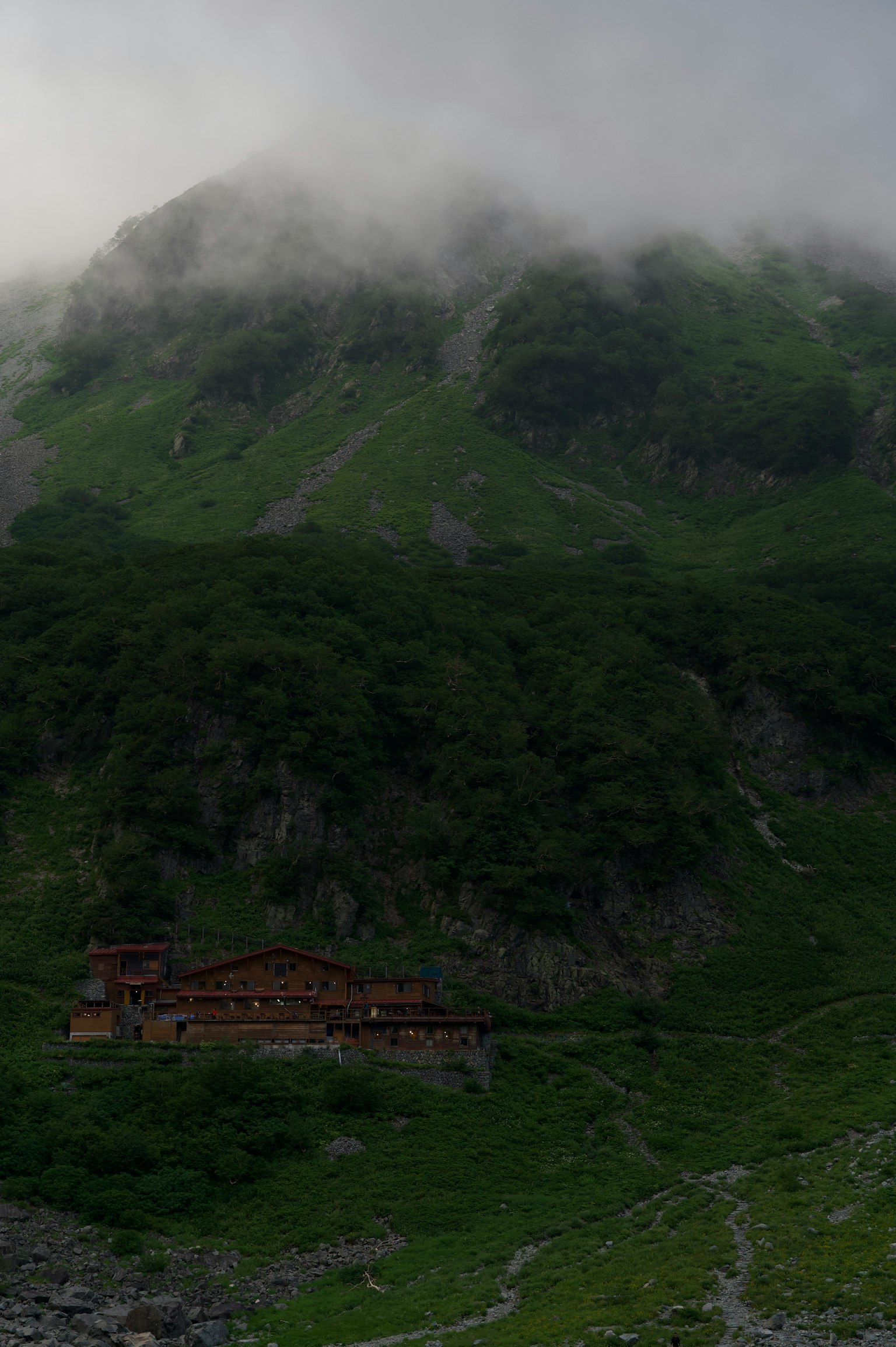 Un vecchio edificio immerso in montagne verdi avvolte nella nebbia