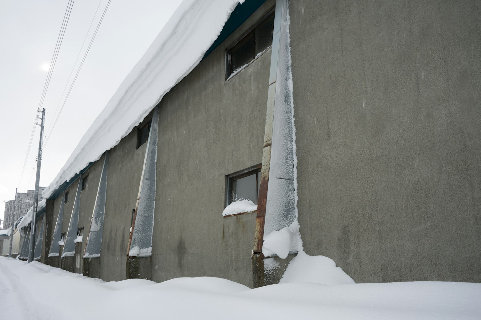 Vista laterale di un edificio coperto di neve Ghiaccioli pendono dalle finestre Scenario invernale