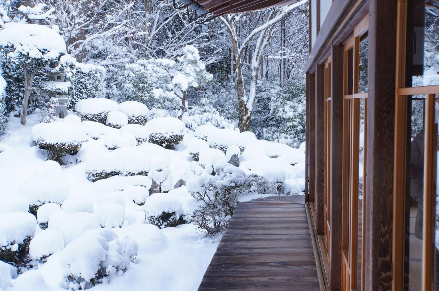 Schneebedeckter Garten mit Holzterrasse und ruhiger Landschaft