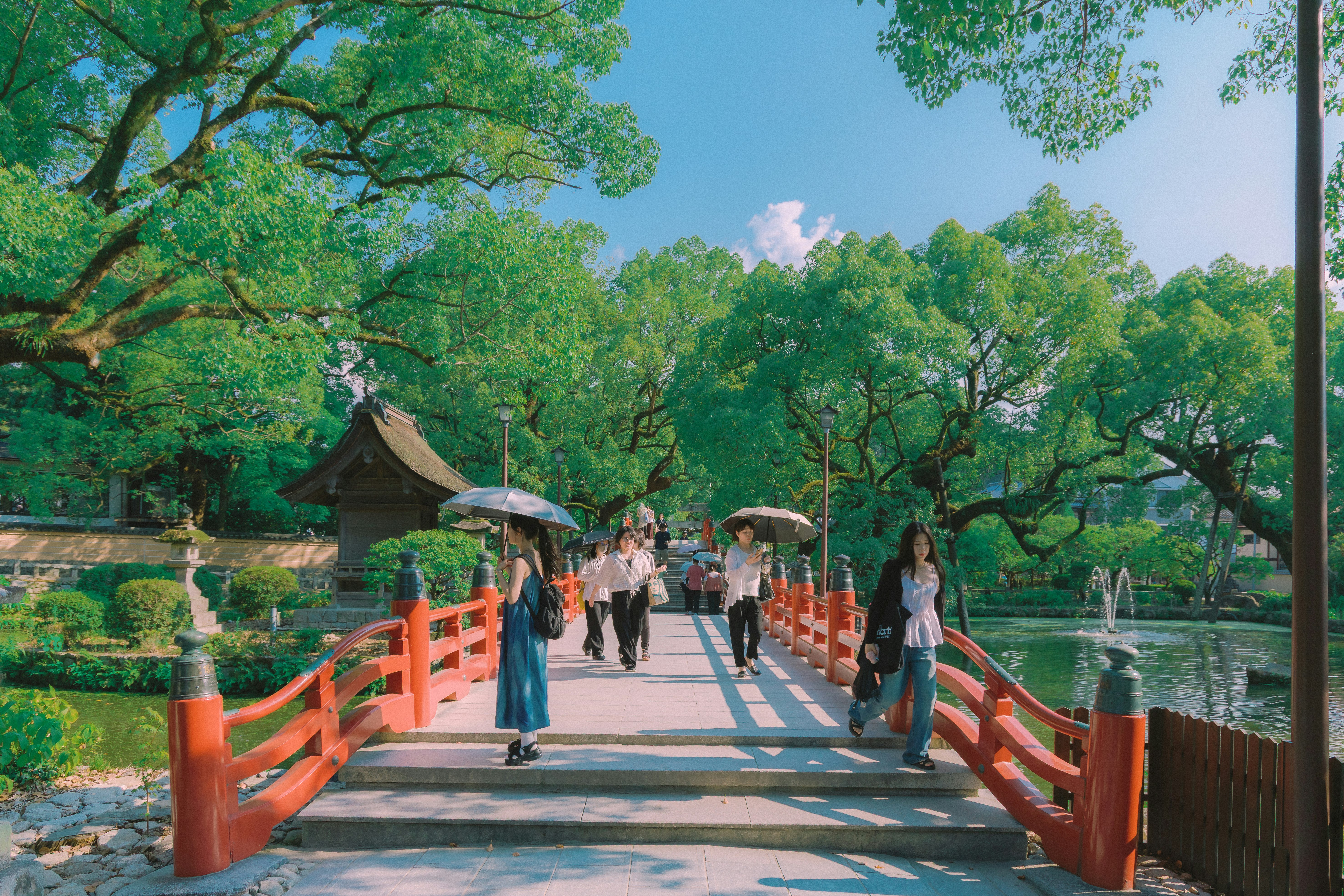 緑の並木と朱色の欄干が続く庭園の小道