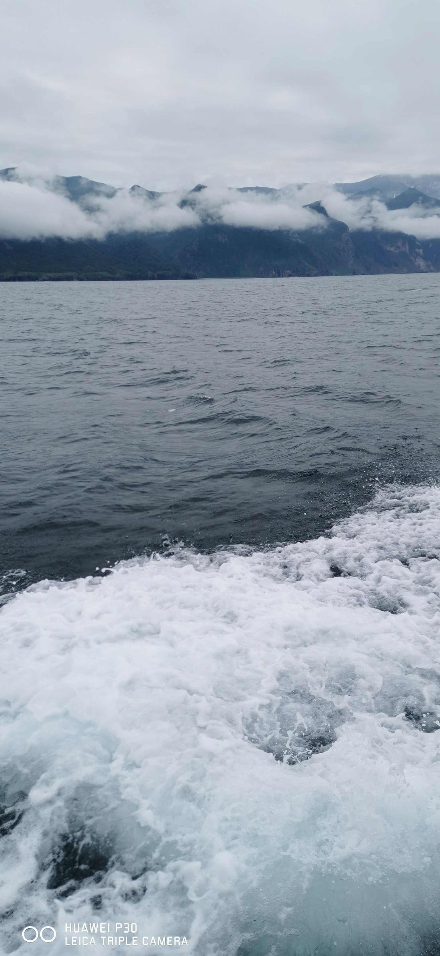 Ruhiges Meer mit nebligen Bergen im Hintergrund