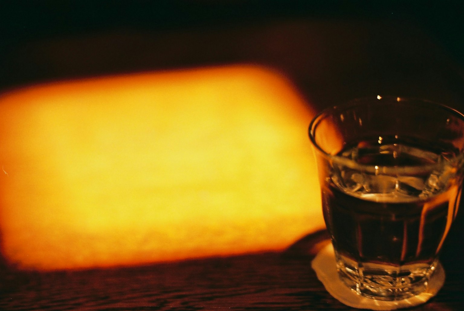 Un bicchiere con una bevanda che riflette una luce calda