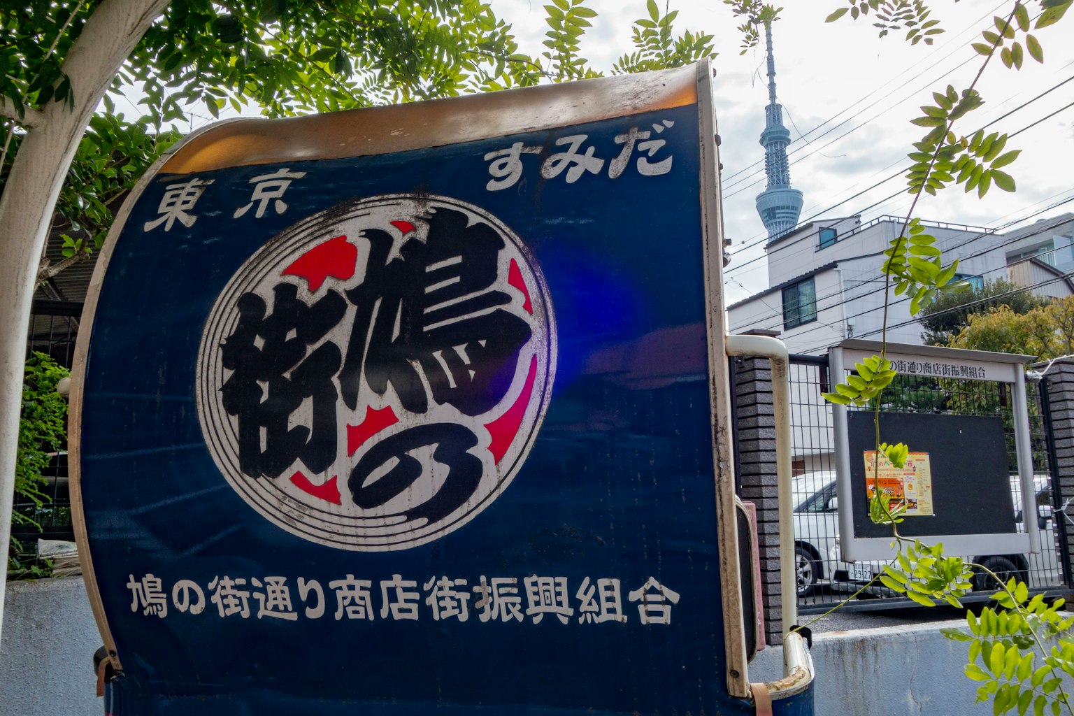Schild in Tokio mit dem Sky Tree im Hintergrund einer Einkaufsstraße