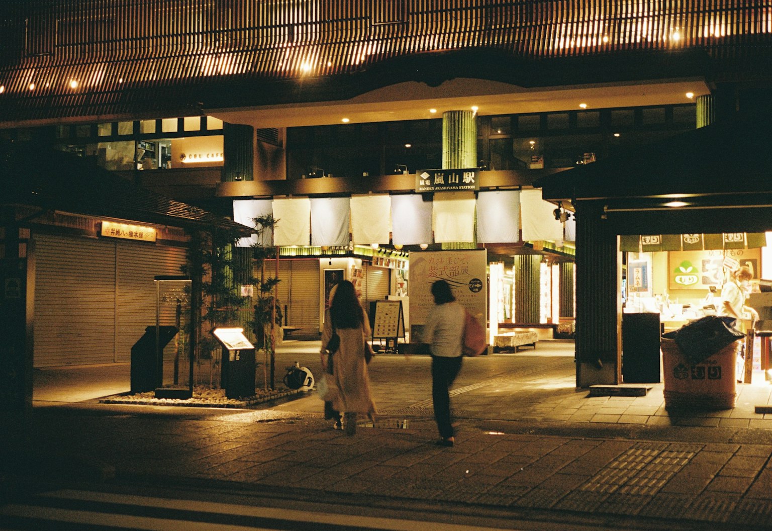 Couple marchant dans la soirée avec des vitrines éclairées en arrière-plan