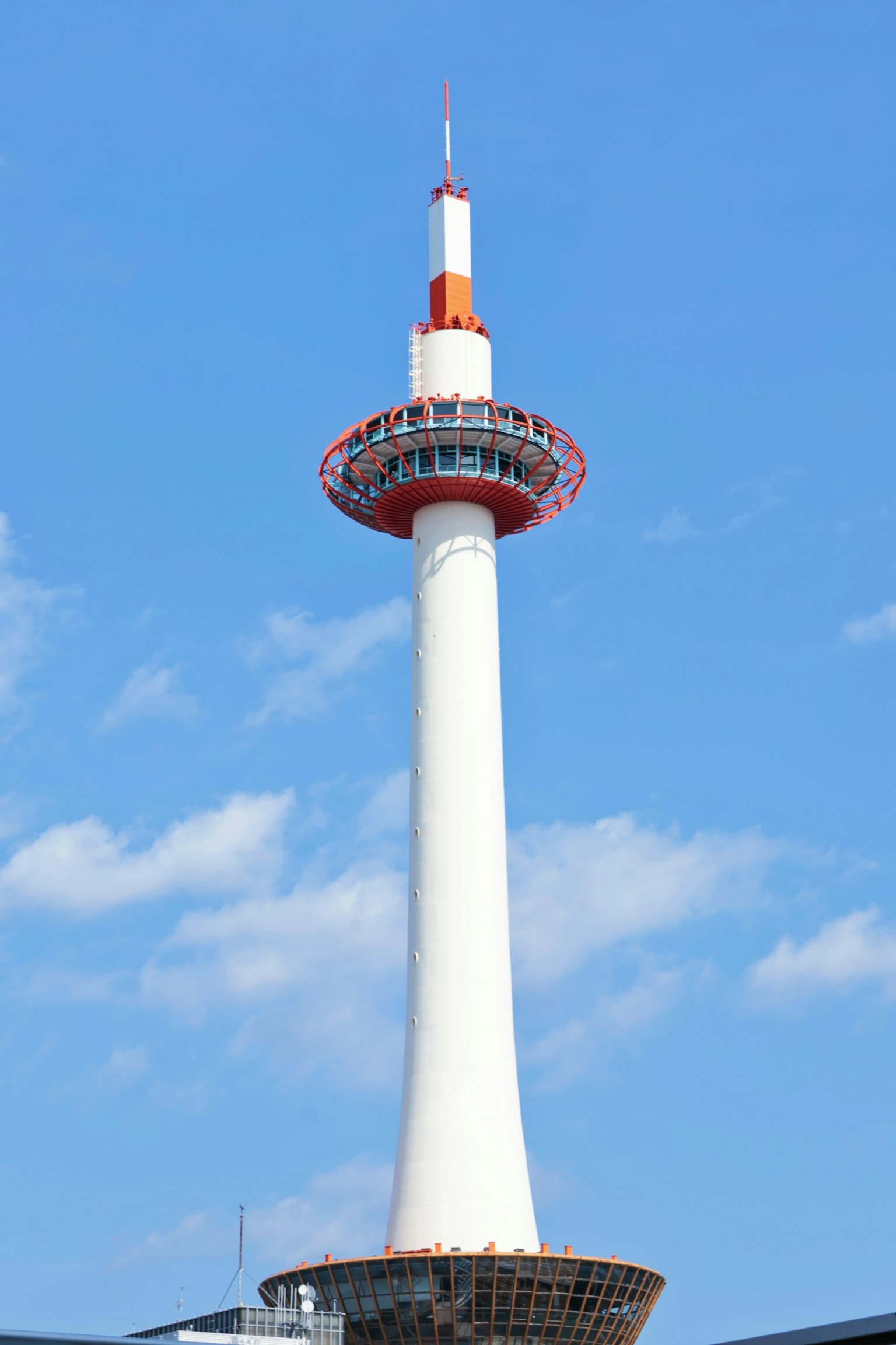 Kyoto Tower with a white column and red observation deck against a blue sky
