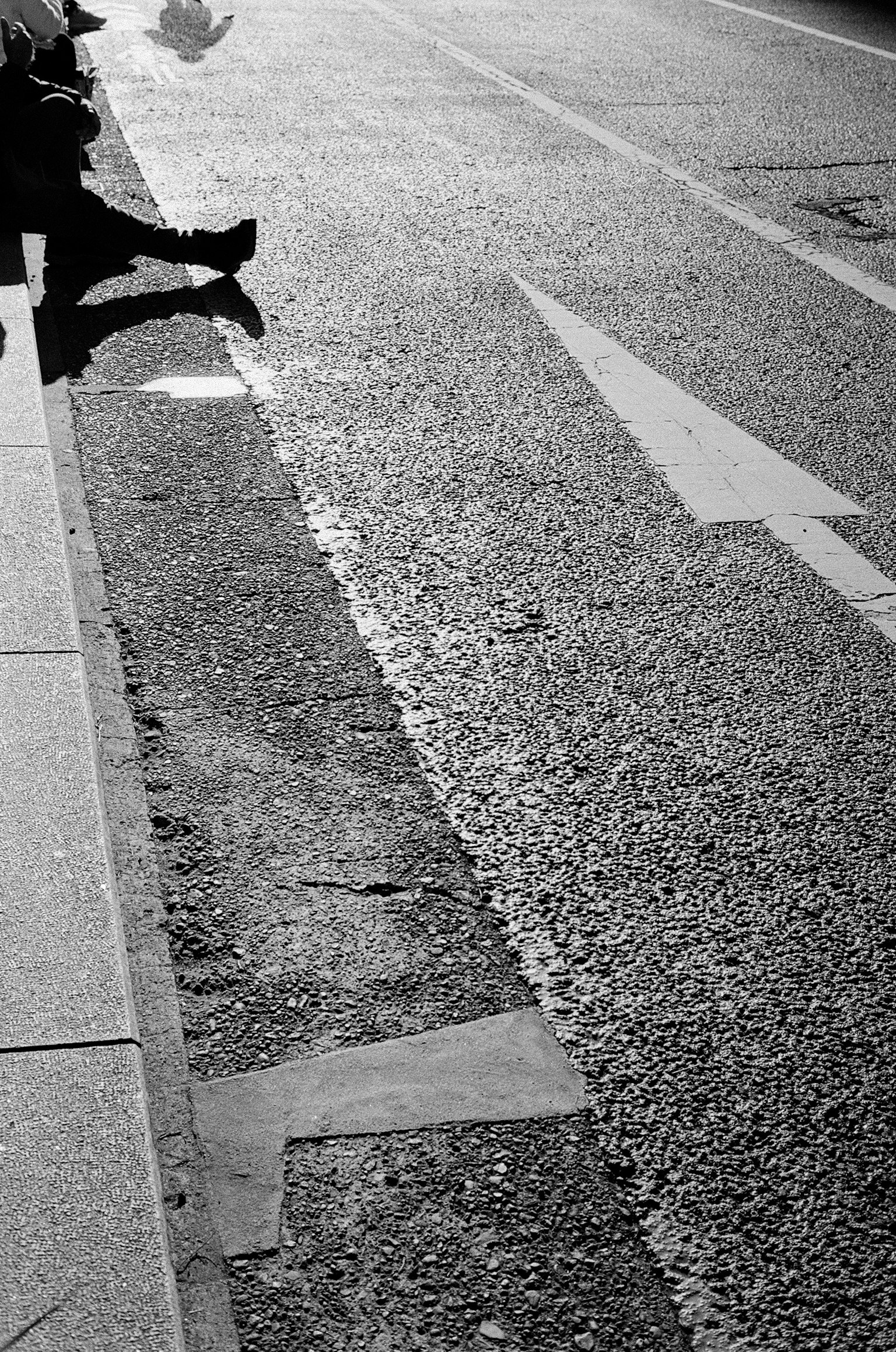 Black and white image showing part of a road with an arrow marking