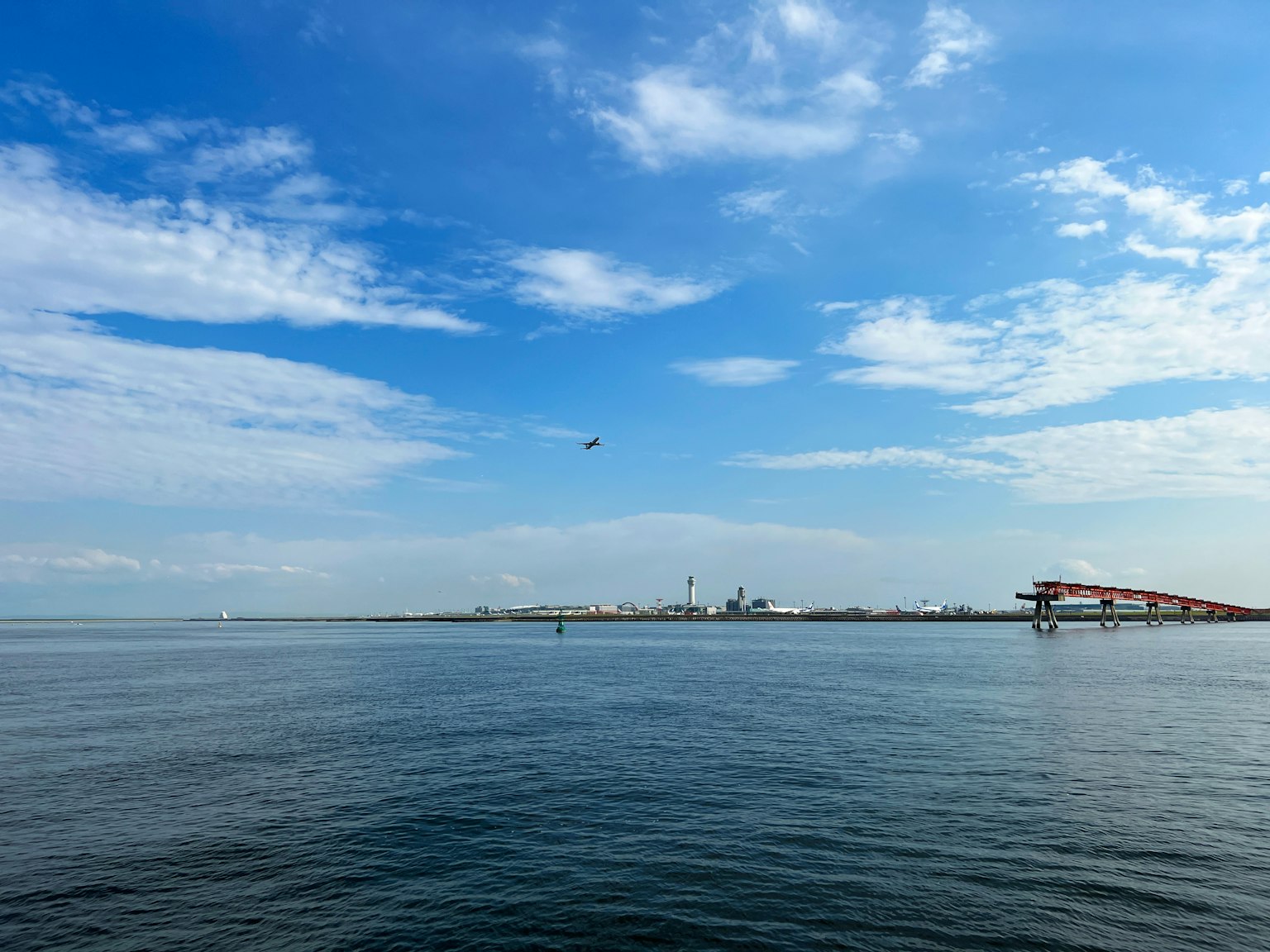 Panoramablick auf blauen Himmel und ruhiges Meer mit sichtbarem Hafen und Gebäuden