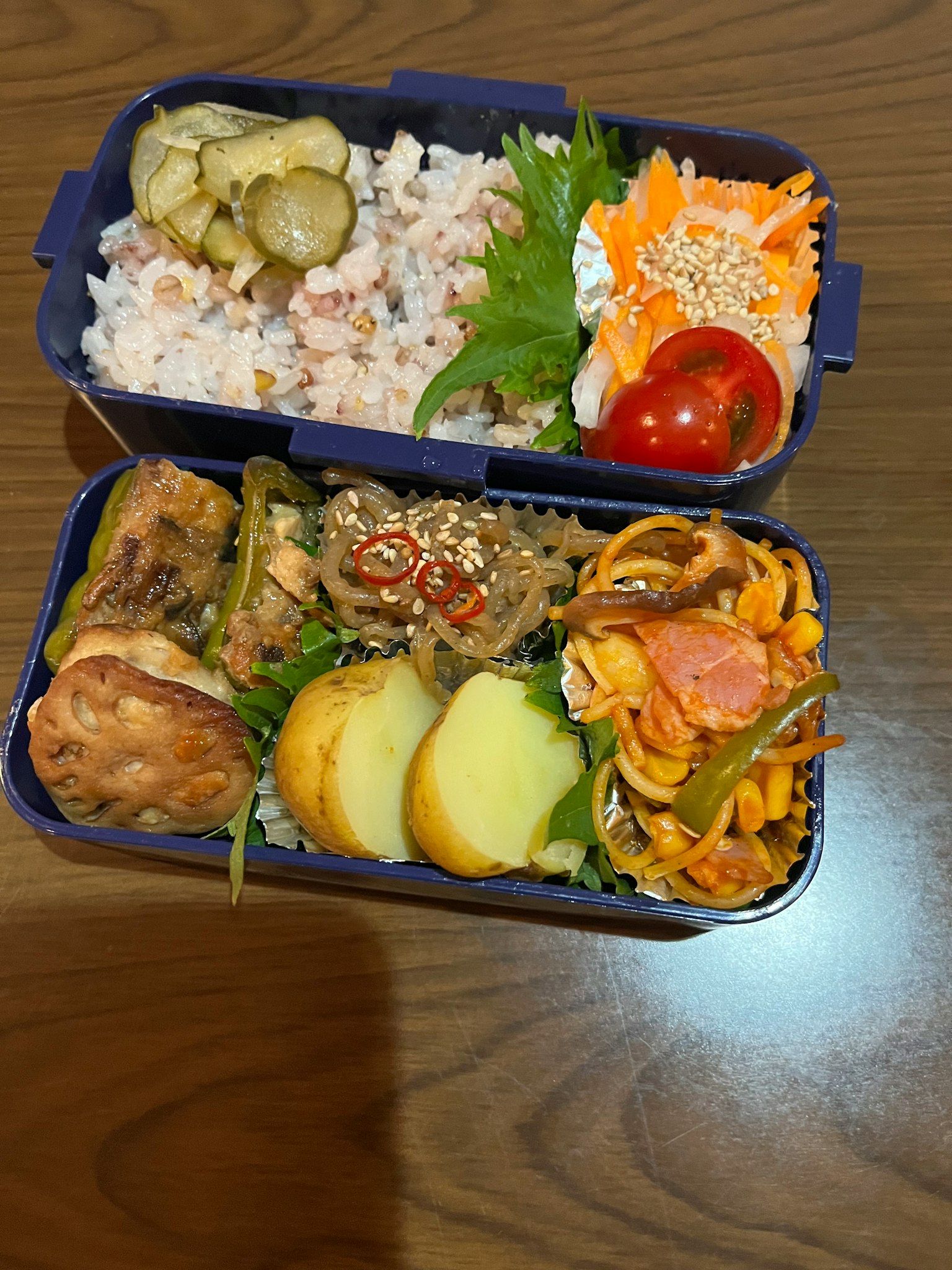 一个便当盒里装满了米饭、腌菜、沙拉、肉类菜肴、意大利面和水果