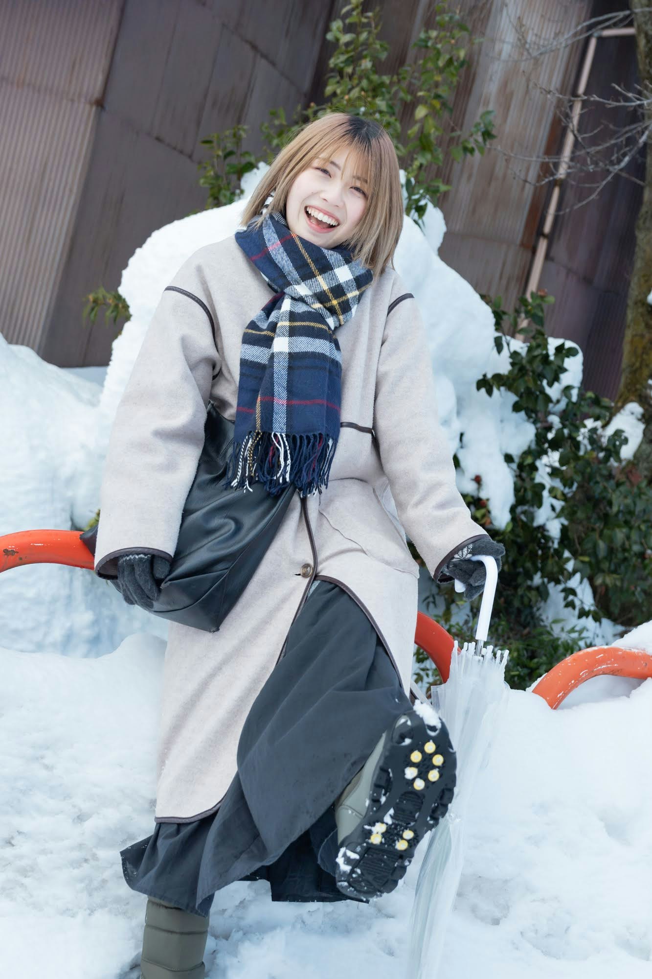 donna sorridente con cappotto e sciarpa in un giardino innevato all’aperto