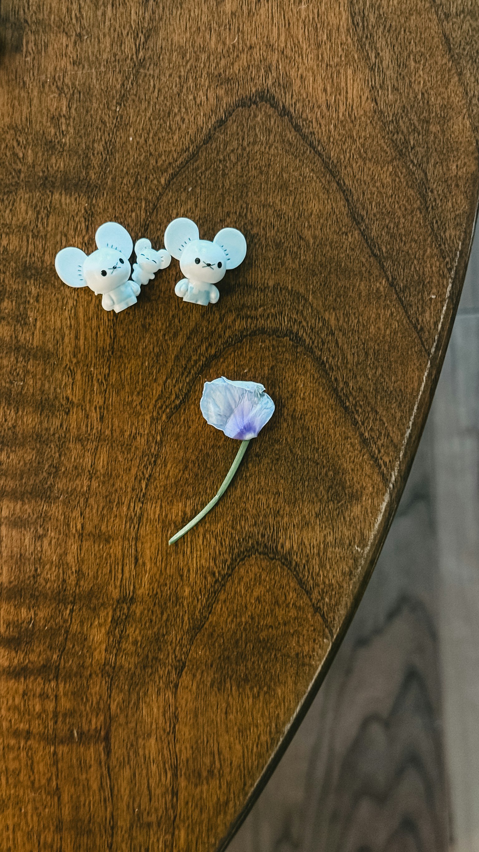 Due figurine a forma di topo e un fiore viola su un tavolo di legno