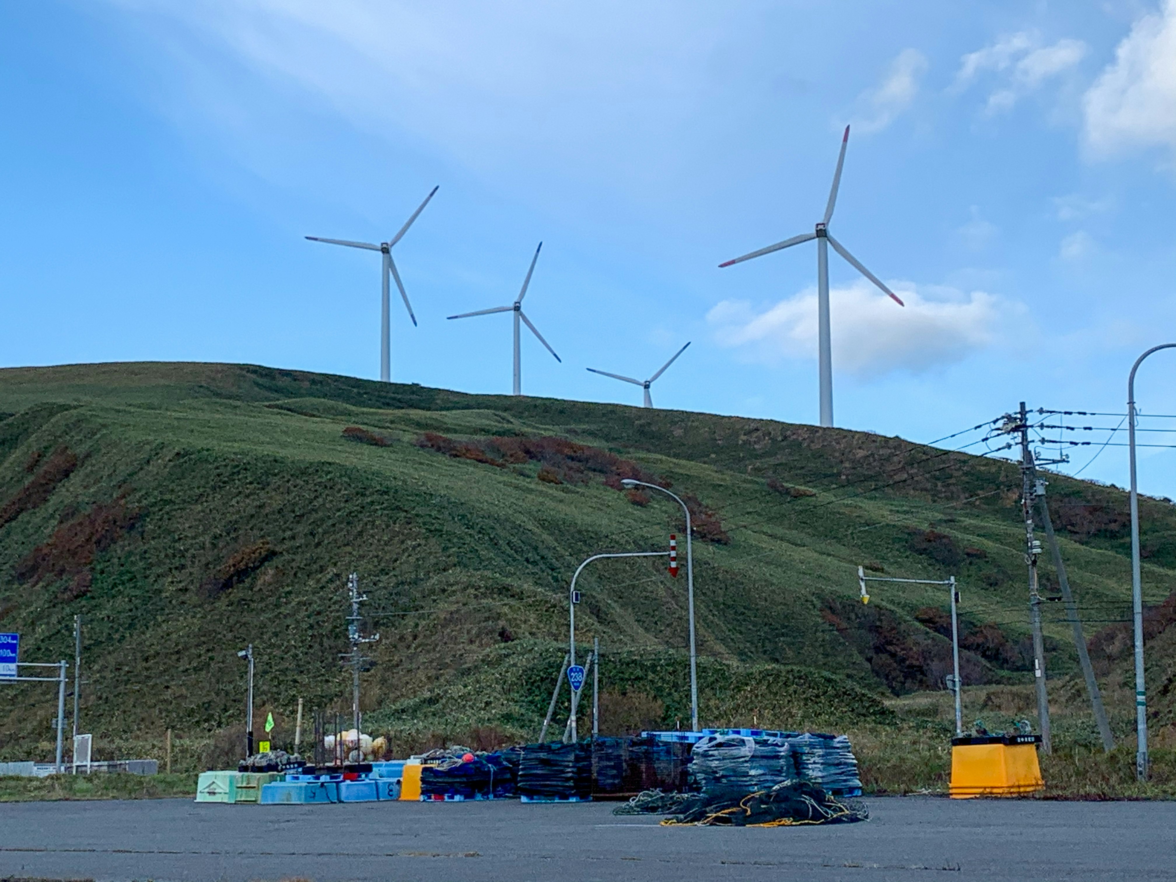 Wind turbines and power infrastructure on a grassy hillside