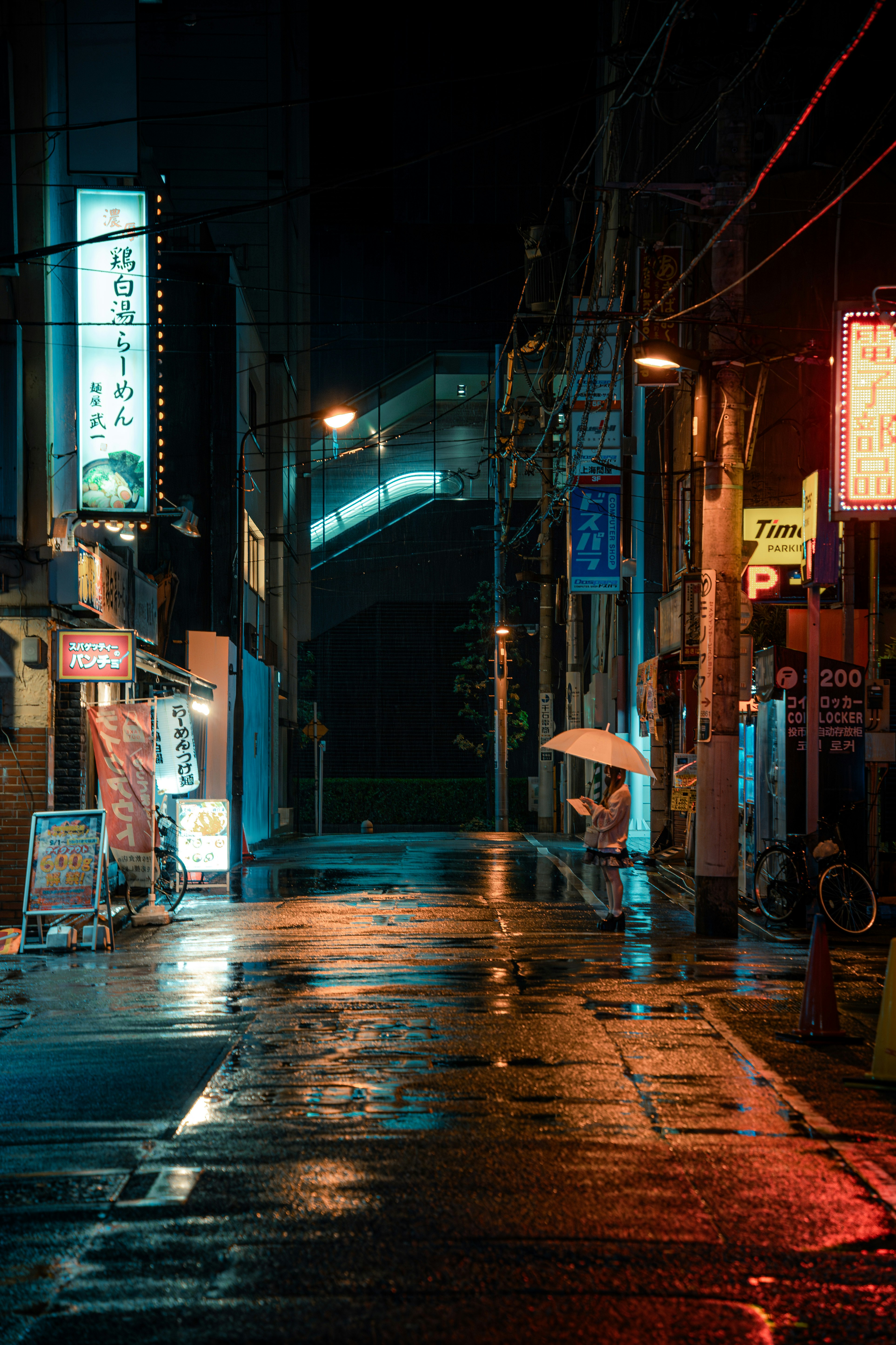 雨上がりの路地に並ぶ看板と自転車のある夜景