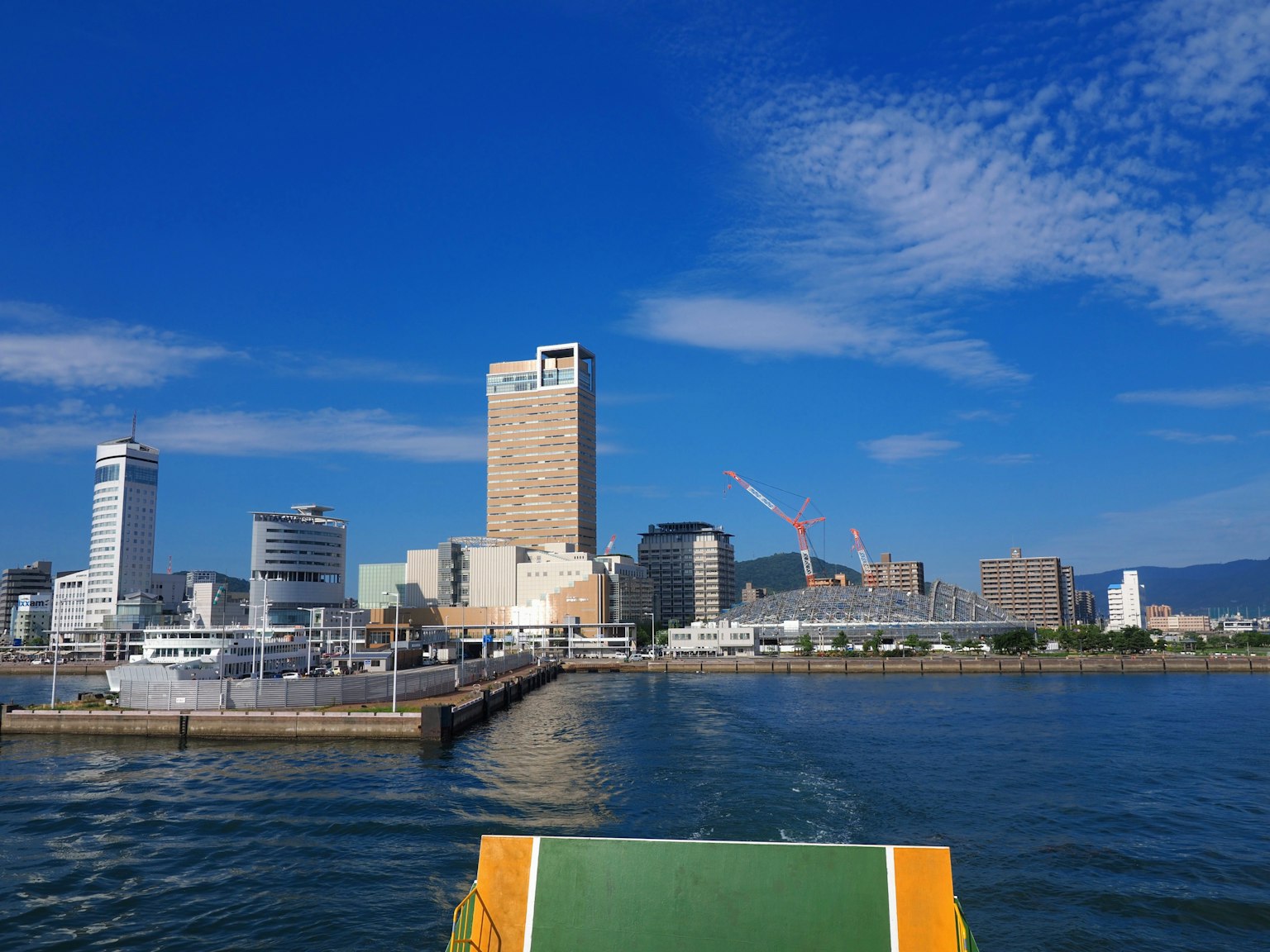 蔚藍天空下的城市風景，高樓大廈與起重機