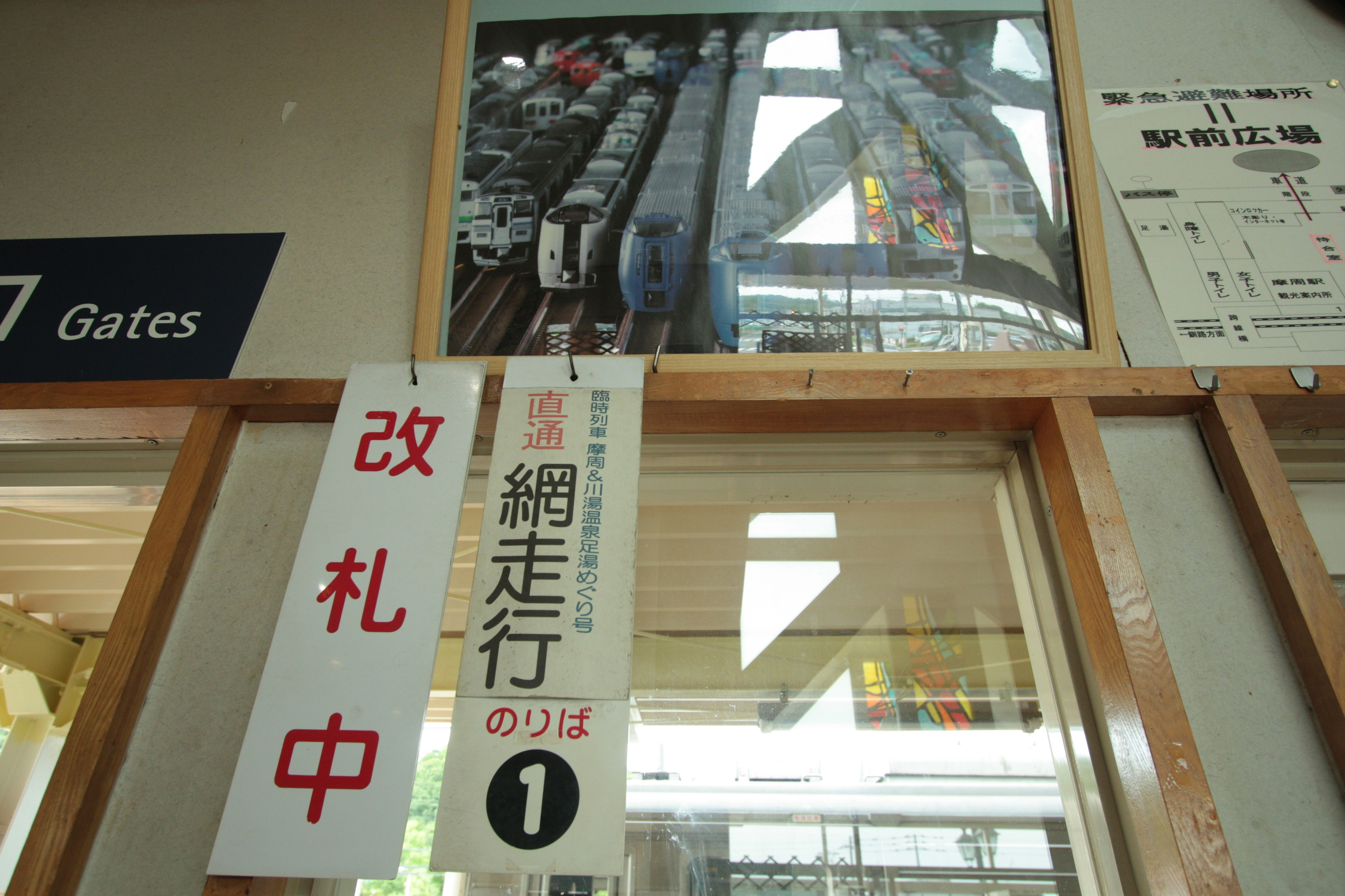 改札口の案内表示と掲示物が並ぶ駅構内の通路