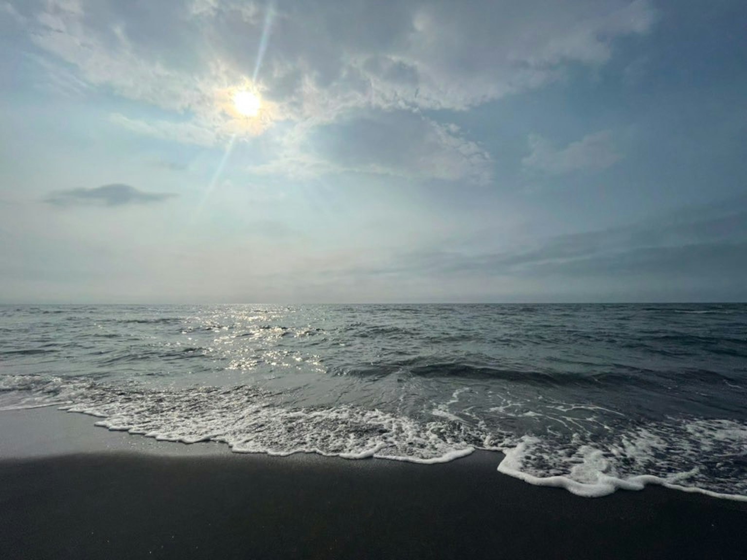 Seascape with waves lapping on the shore and sunlight reflecting on the water