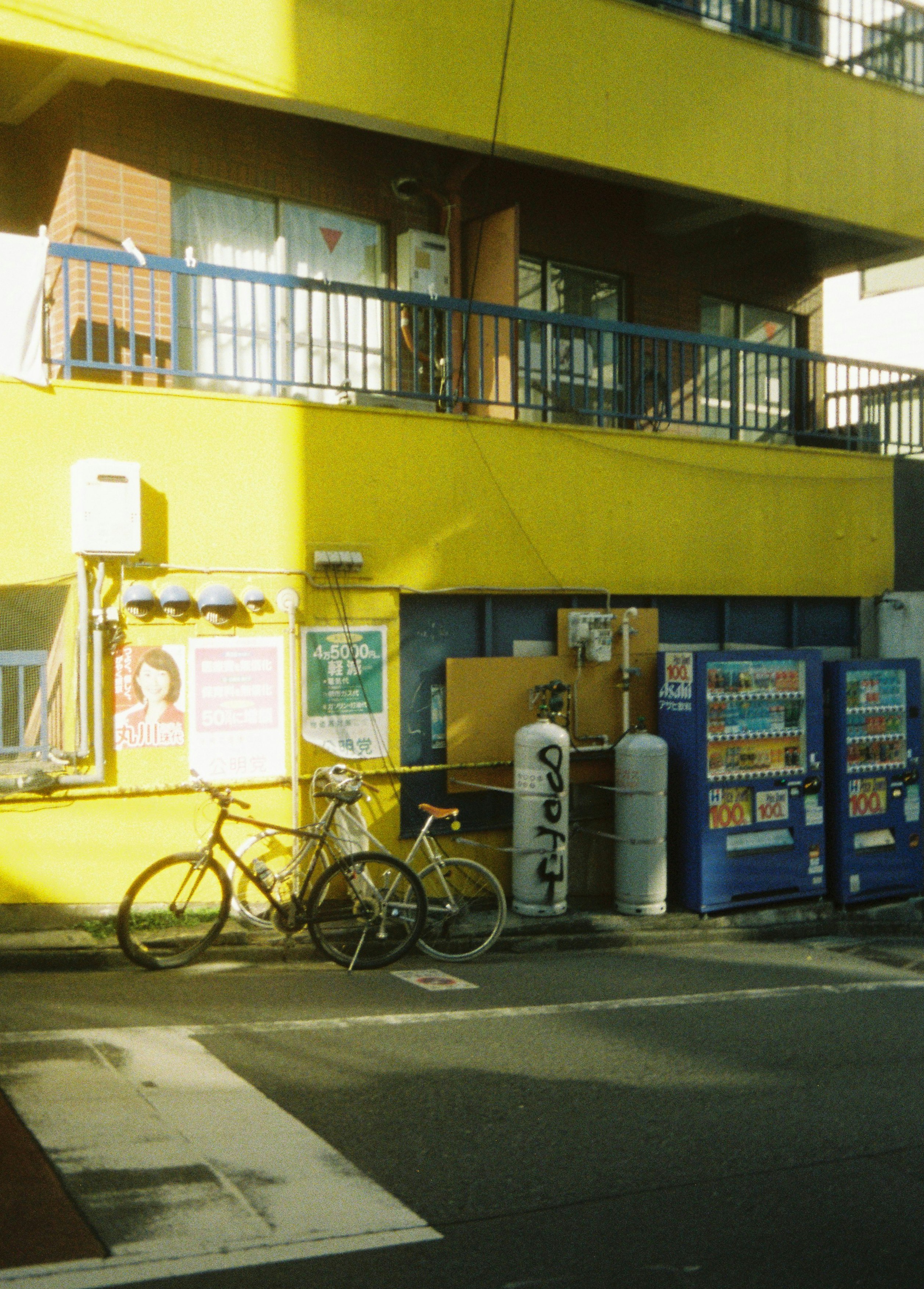 路地の自転車と店先の看板が並ぶ商店街の軒先