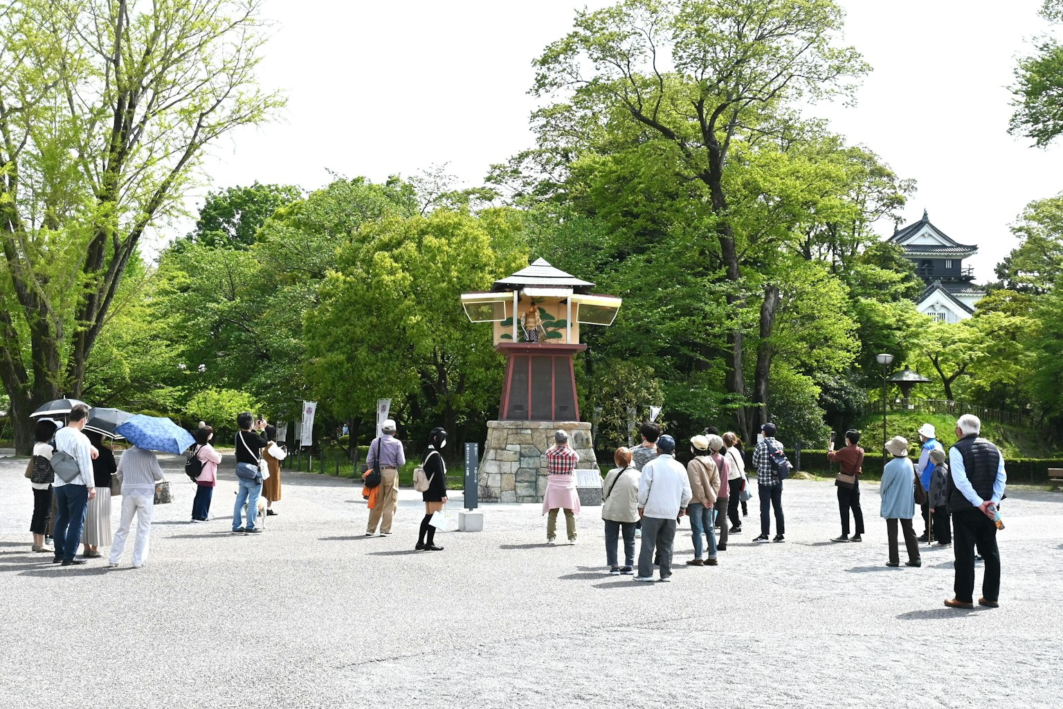 Quảng trường công viên đông đúc với mọi người tụ tập Cây xanh và tháp truyền thống có thể nhìn thấy