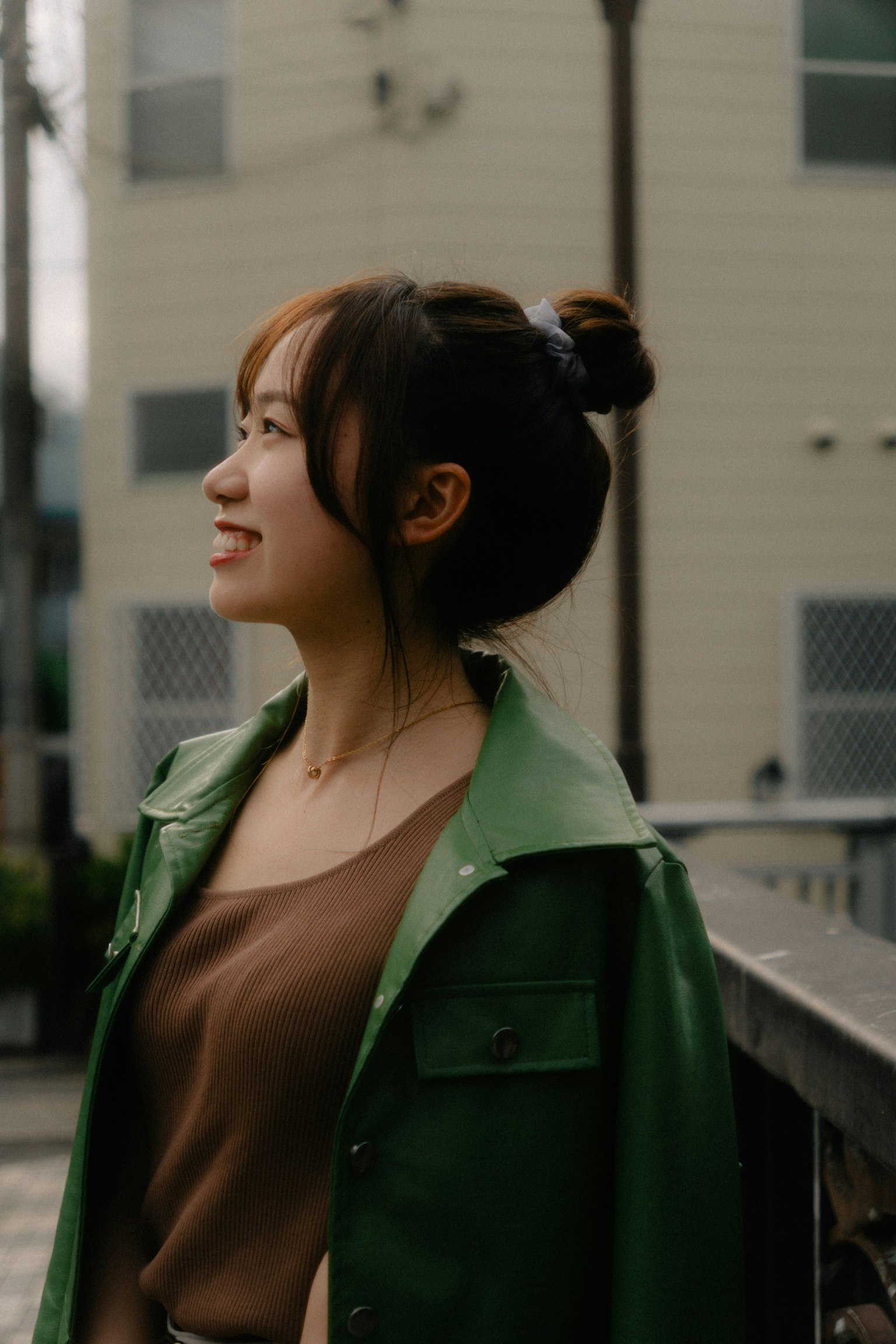 穿著綠色夾克的女性微笑著側身看著