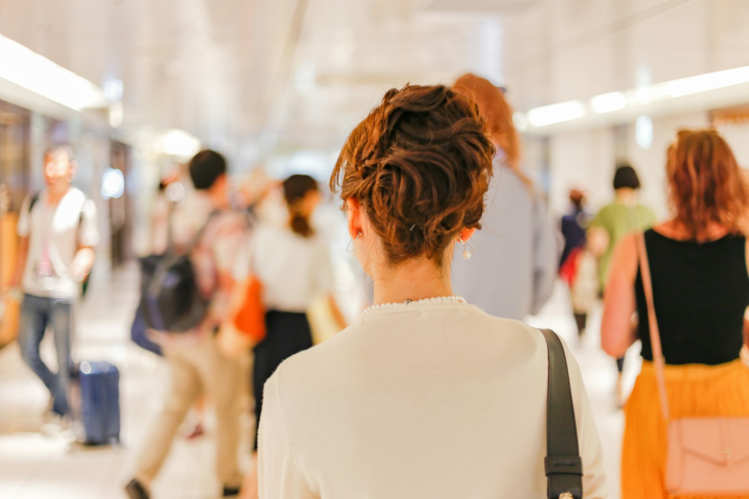 Una mujer vista desde atrás en un pasillo de estación concurrido