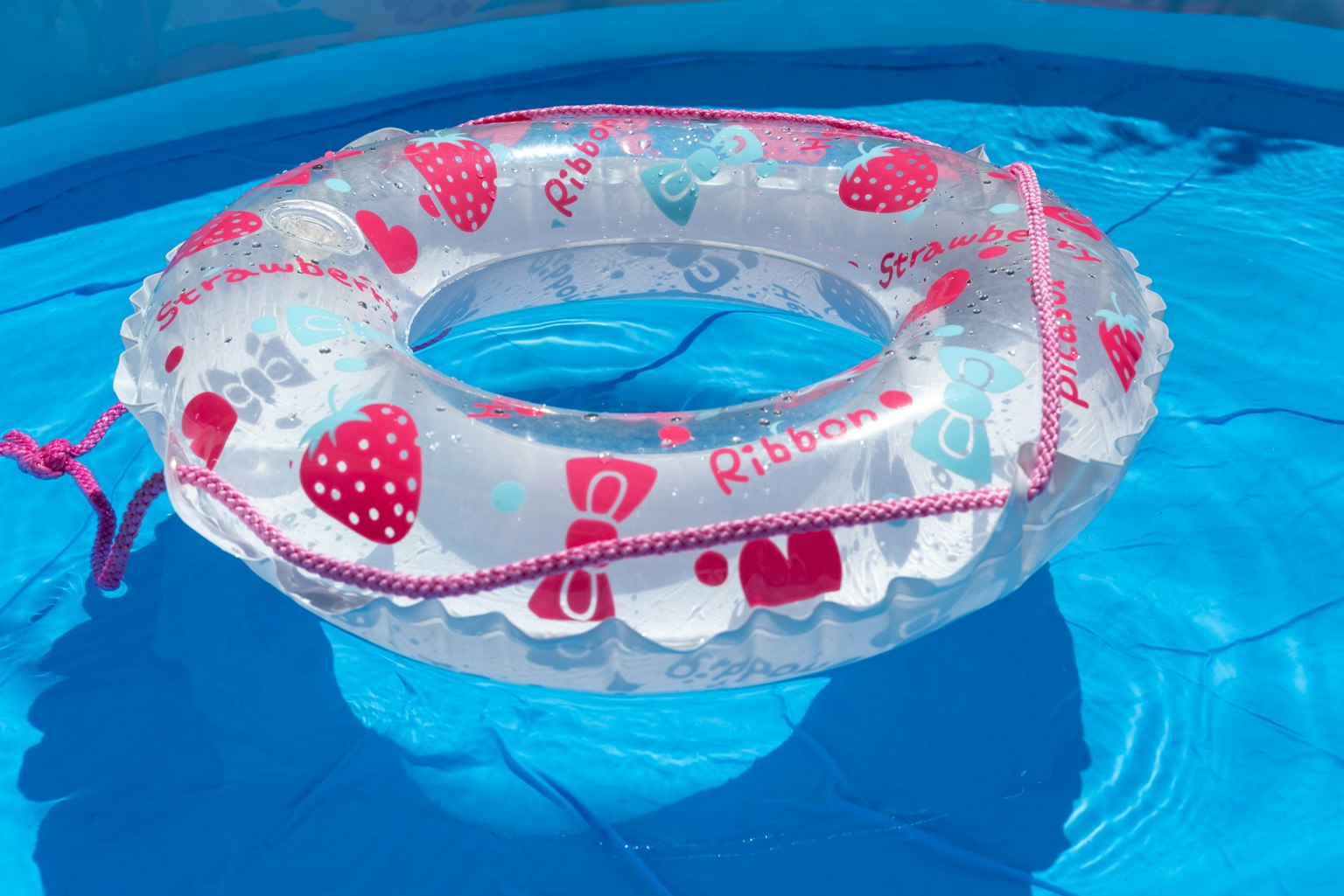 A transparent inflatable ring floating in blue pool water