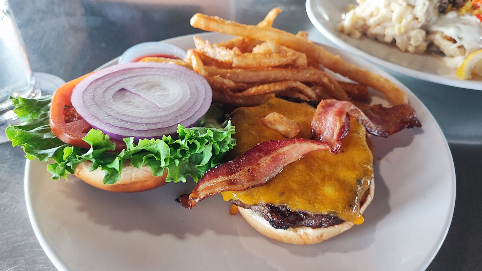 Burger bacon dengan selada tomat bawang dan kentang goreng