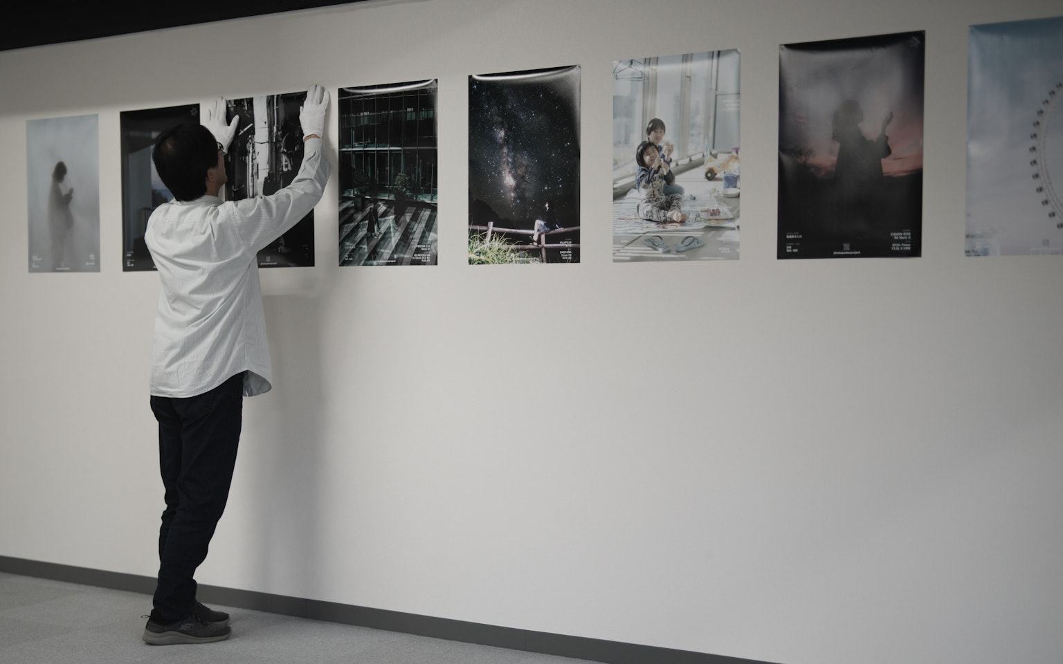 Une personne accrochant des affiches sur un mur avec des œuvres d'art en monochrome