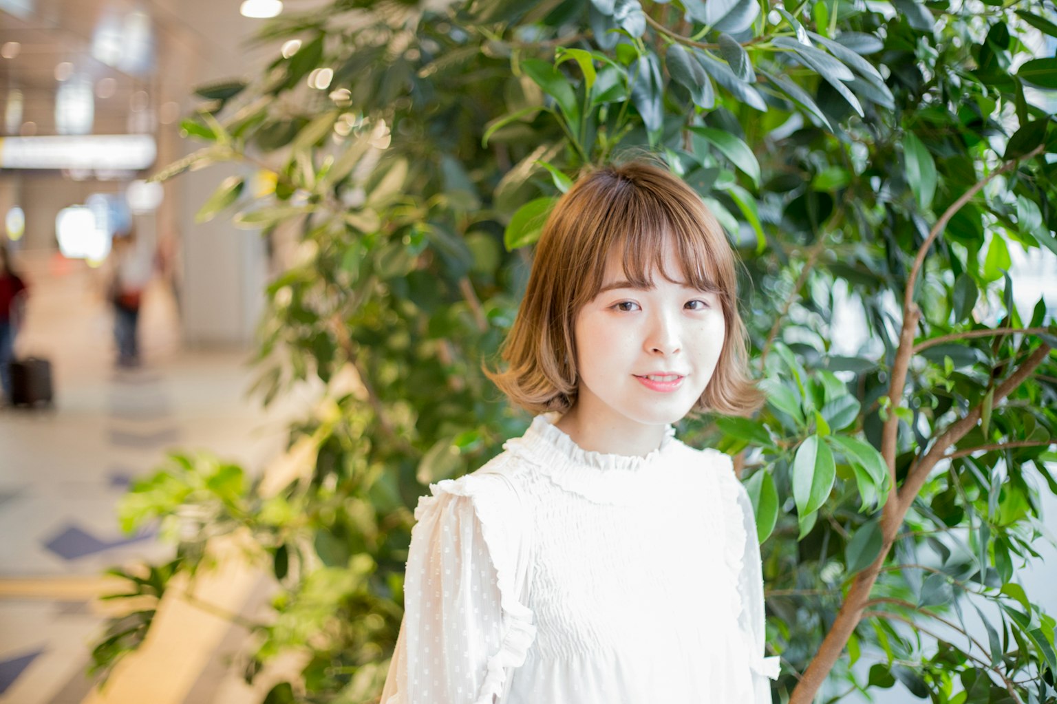 녹색 식물 앞에 서 있는 여성의 초상화