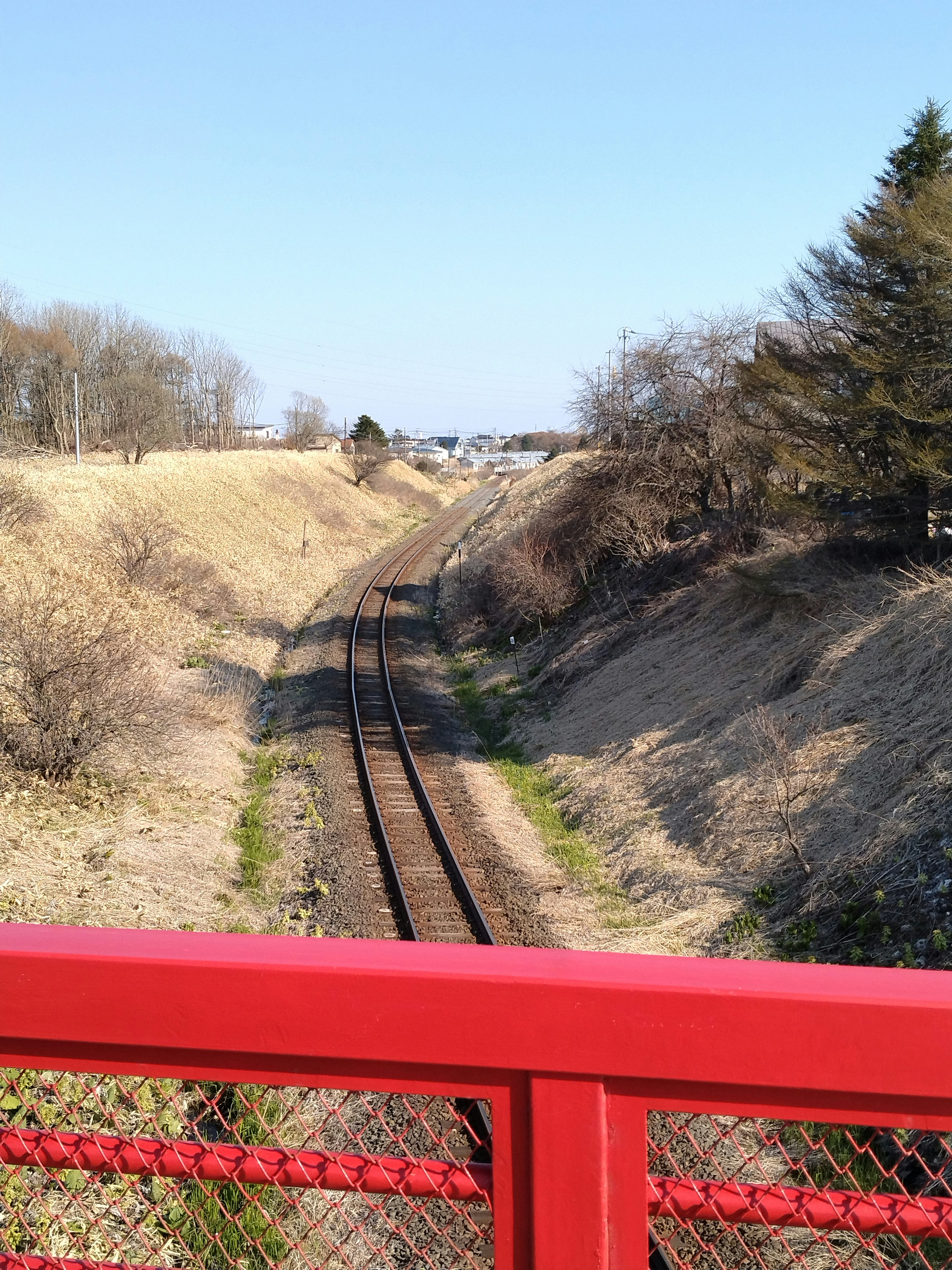 跨線橋から見下ろす線路と郊外の丘