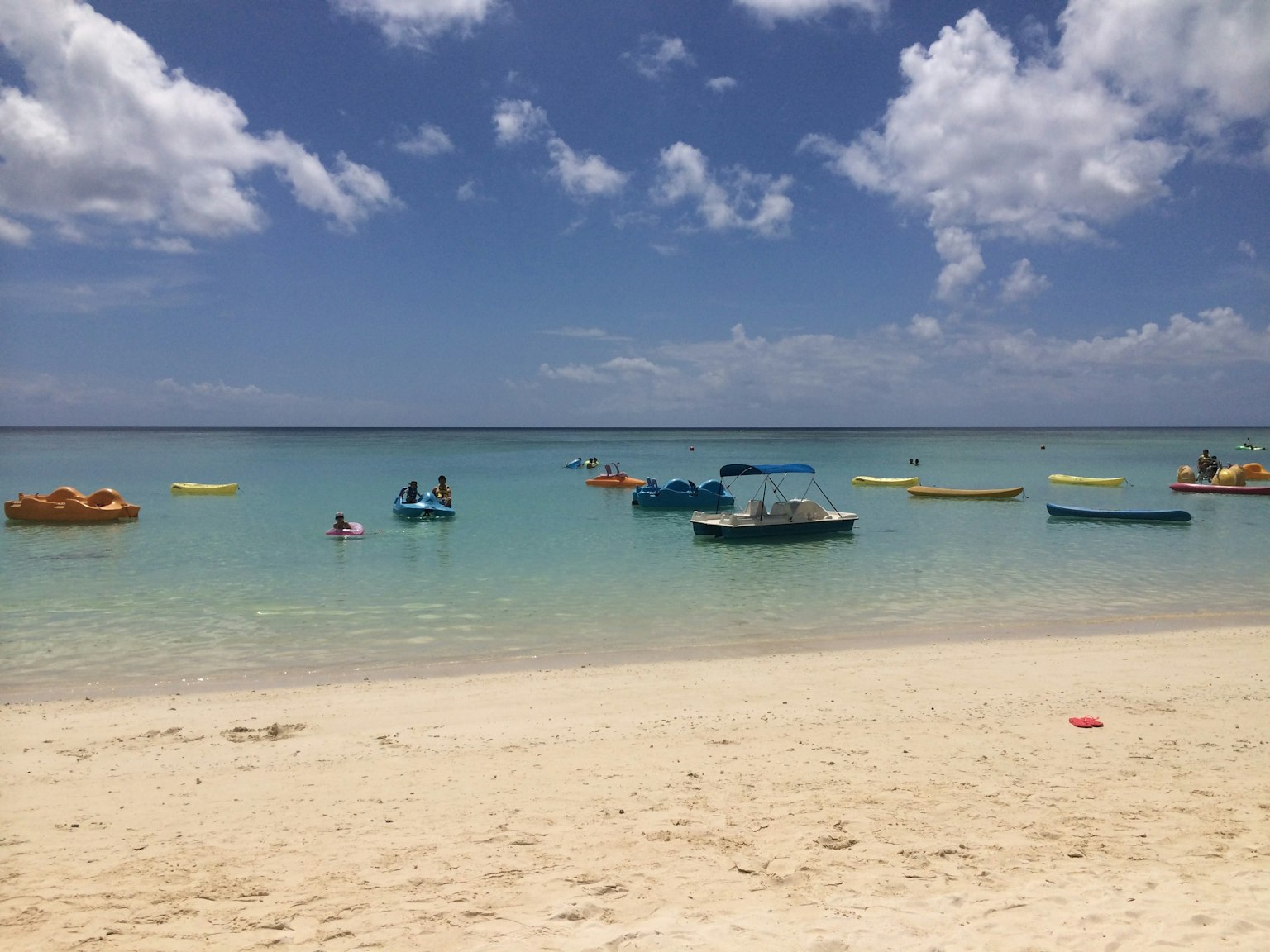 海滩场景，五颜六色的船在清澈的蓝色水面和白色沙滩上