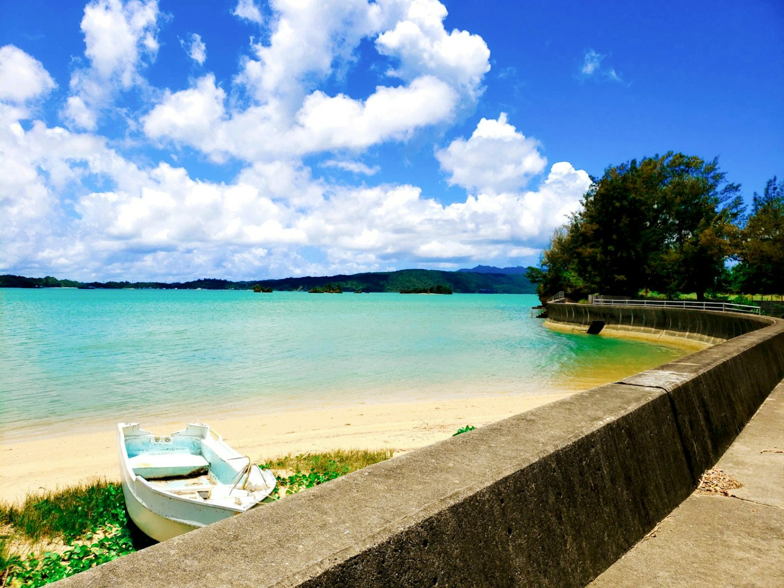 Scenic beach view with turquoise water and fluffy clouds a boat resting on the shore