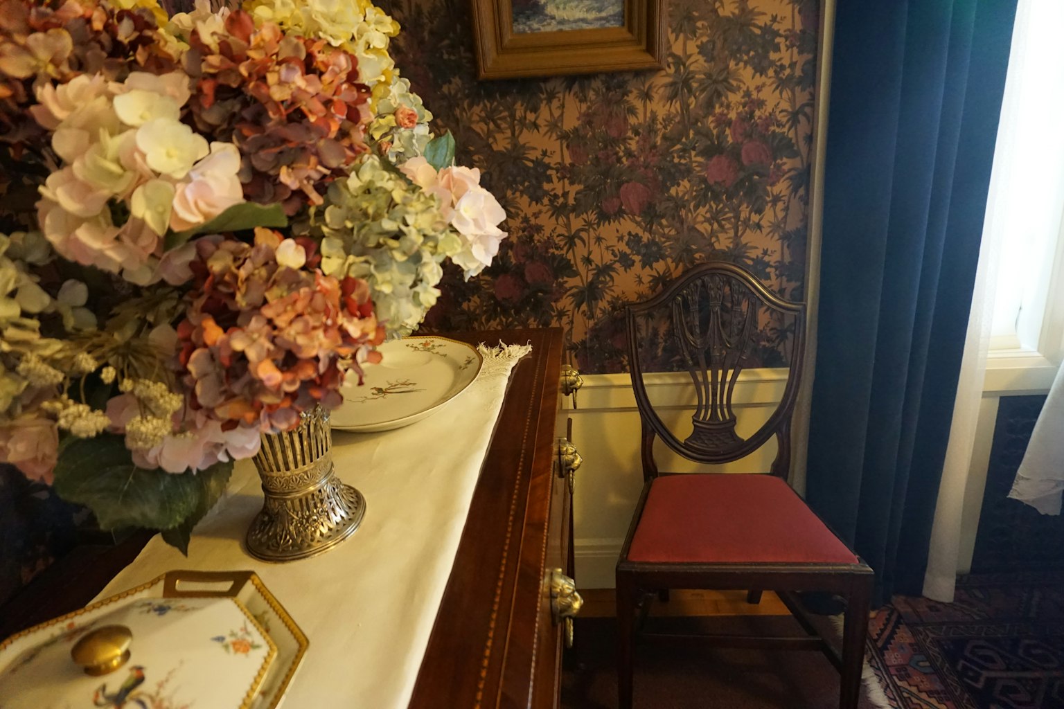 Un angolo di una stanza con un tavolo decorato con un mazzo di fiori colorati e una sedia in legno
