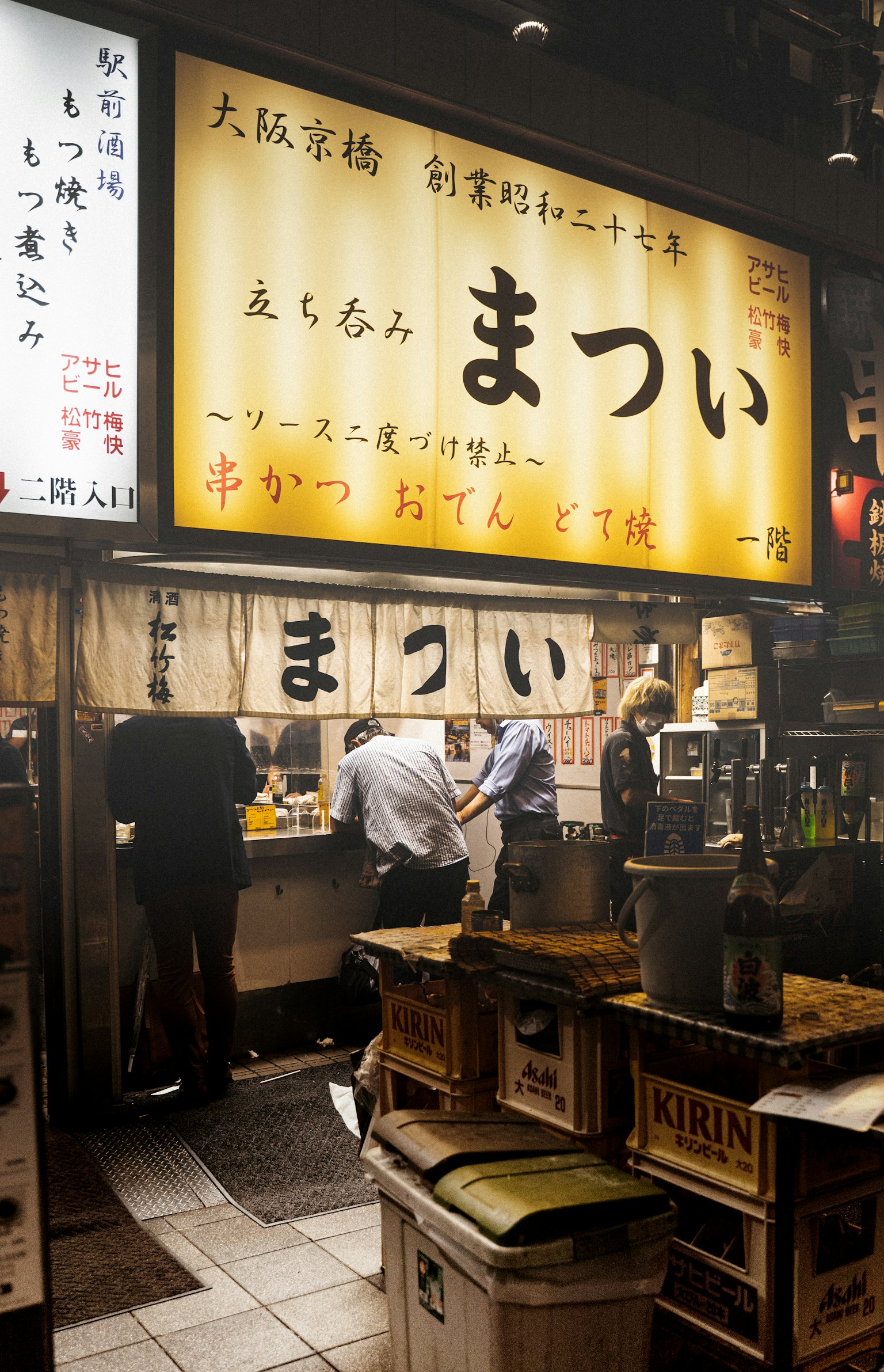 Nội thất của một quán ăn ở Osaka với nhân viên làm việc và biển hiệu sáng
